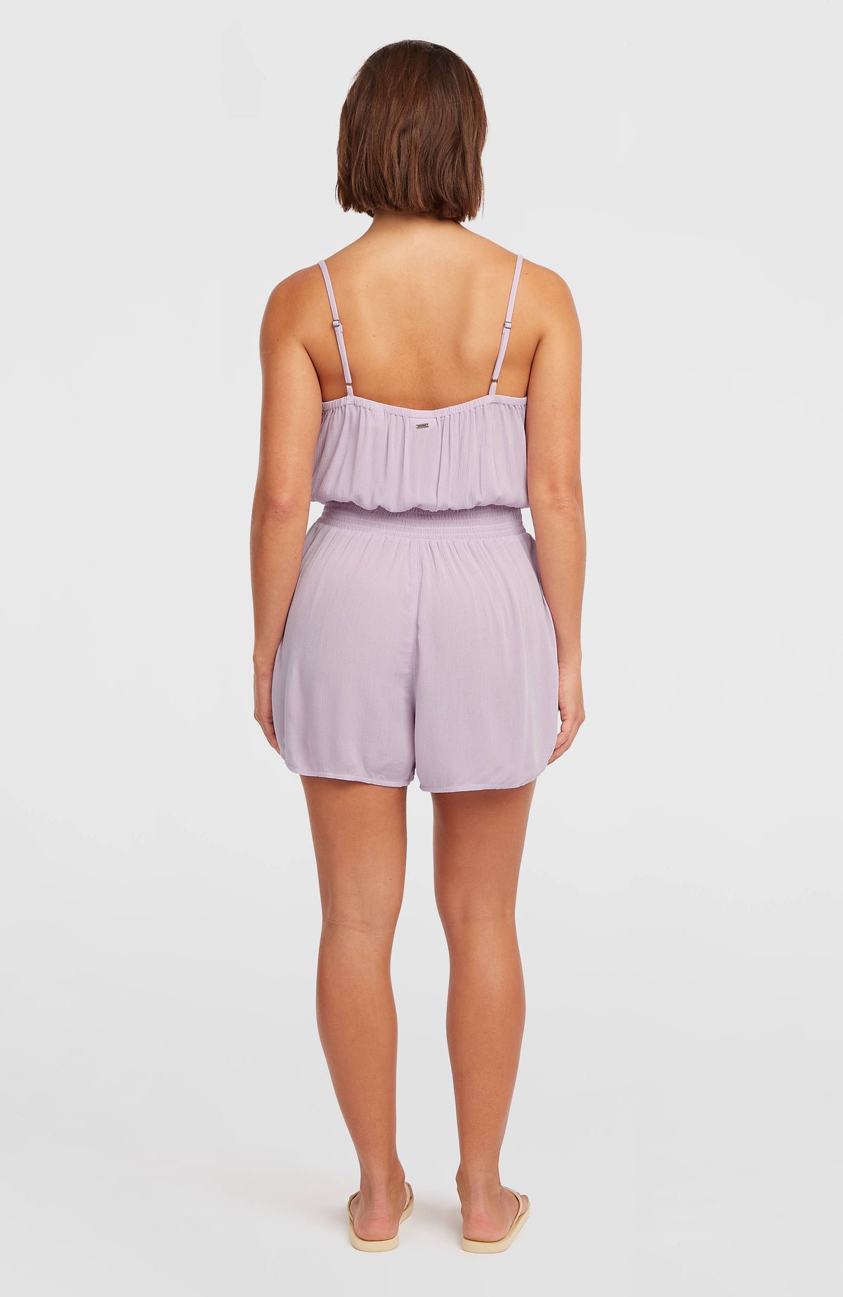 Romper mit Knöpfen und schmalen Trägern für Damen in Lila, Ganzkörperansicht von hinten am Model