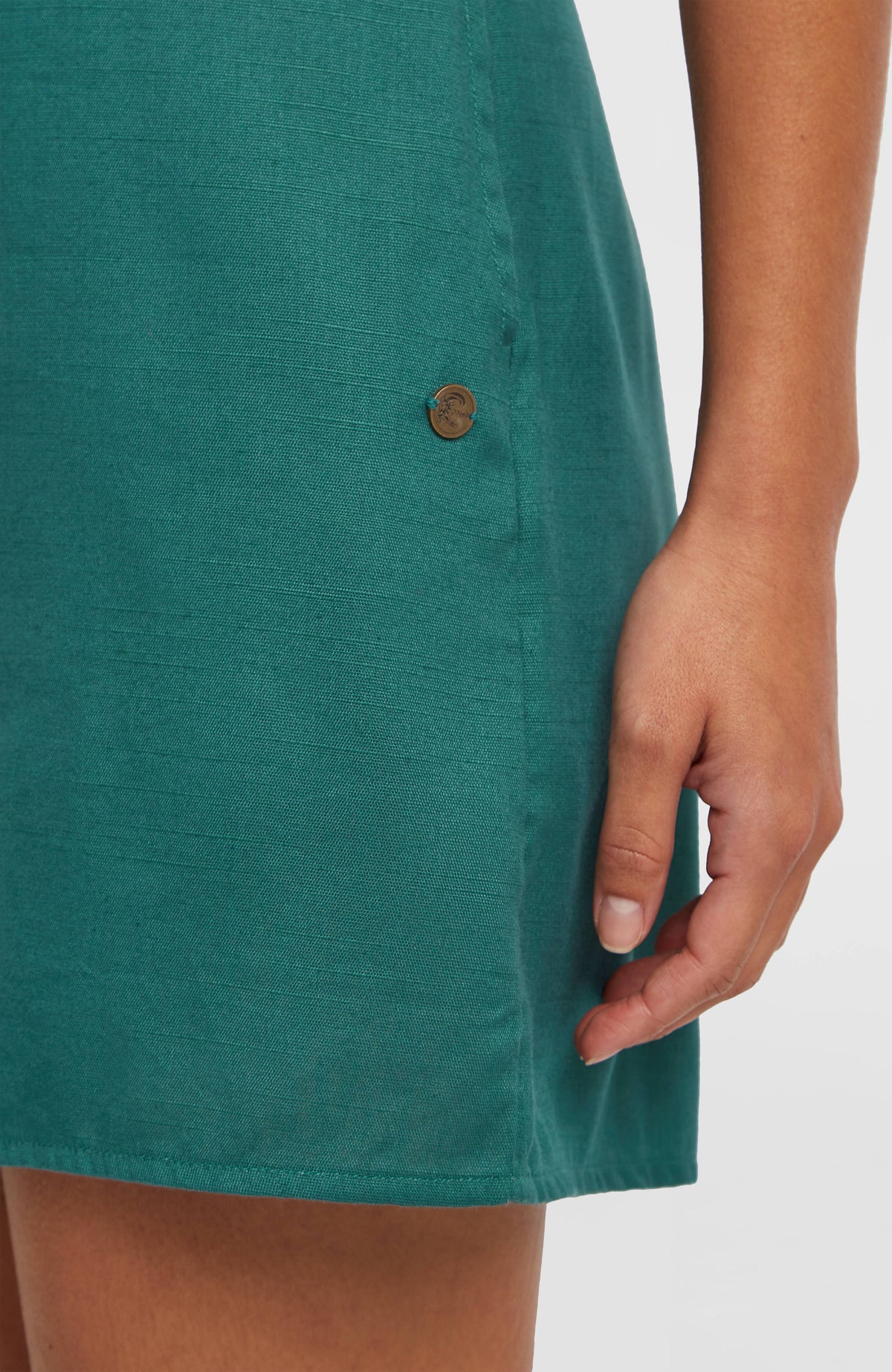 O'Riginals Playsuit für Damen, grün, Nahaufnahme am Model mit kleinem metallischen Logo-Badge an der Seitennaht