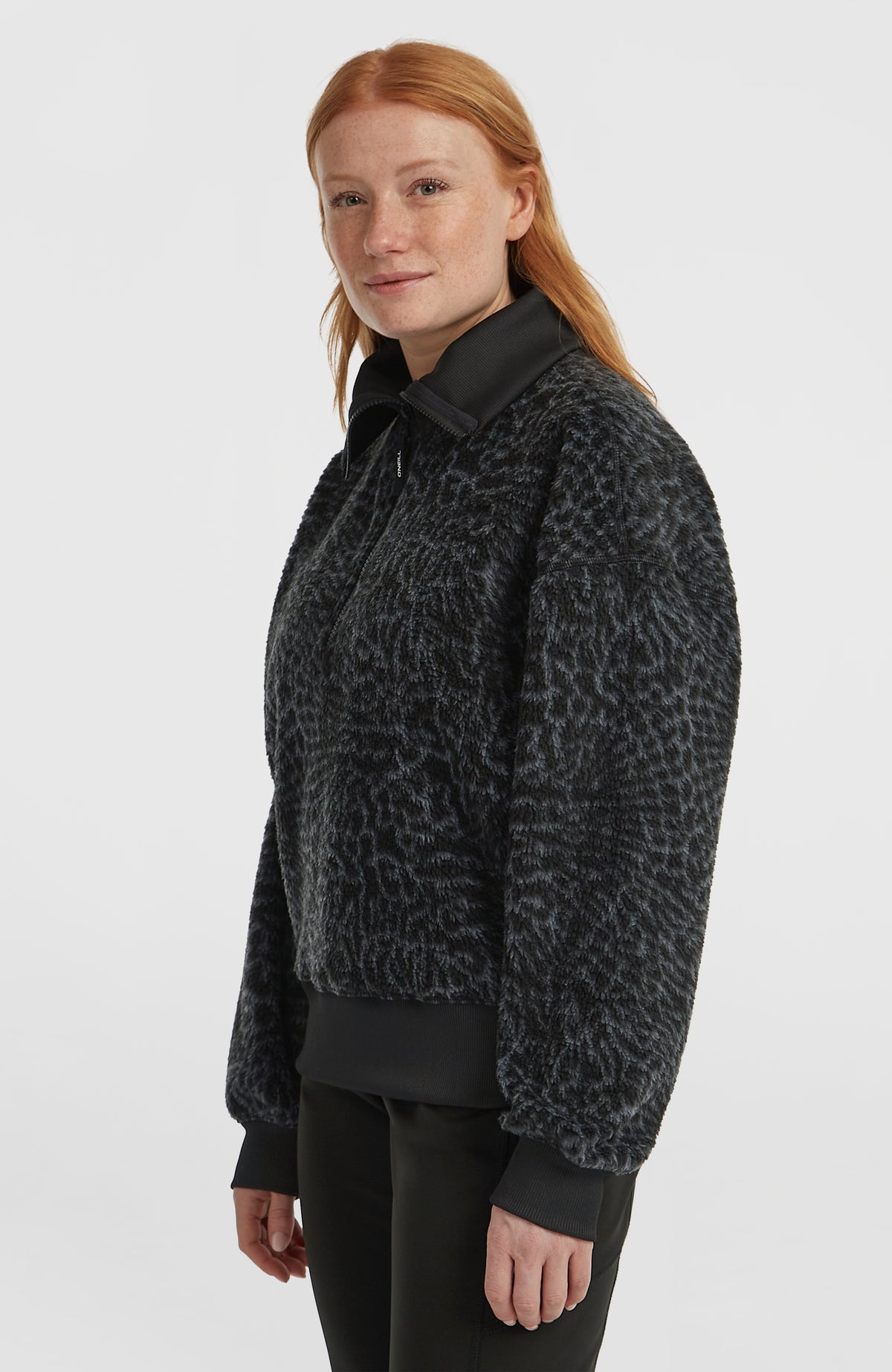 Must-Have Fleecepullover für Damen, schwarz mit Tiermuster in Grau, Halbprofilansicht am Model mit Rippbündchen