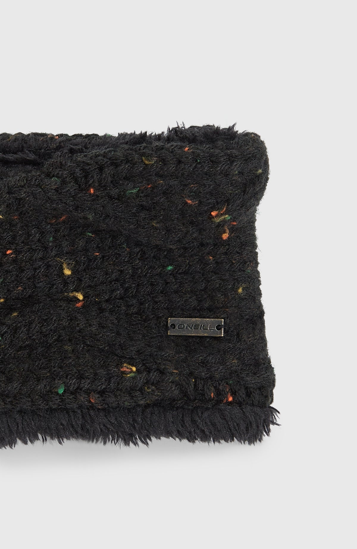 Nahaufnahme des kleinen metallenen Logo-Emblems auf dem schwarzen Nora Stirnband für Damen