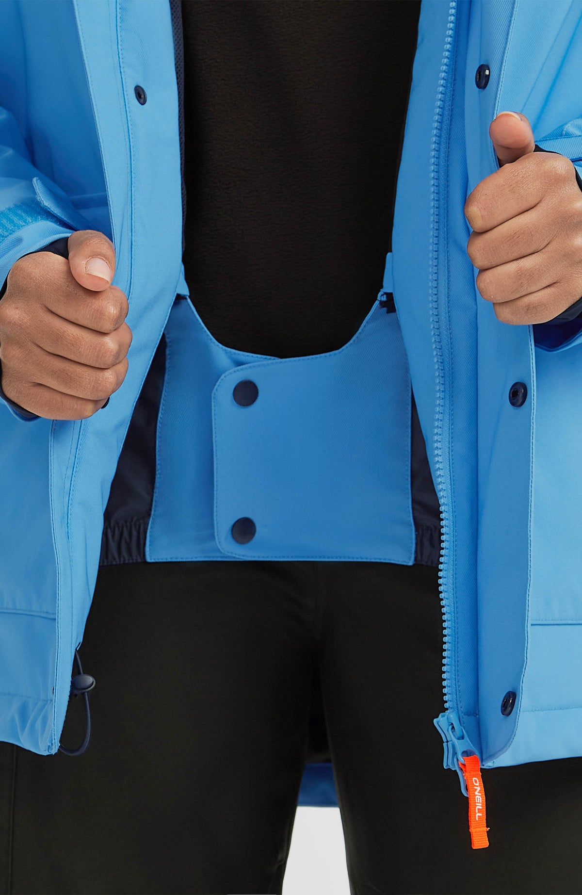Nahaufnahme des Schneefangs mit Druckknöpfen an der blauen FWC'Peak Skijacke am Model