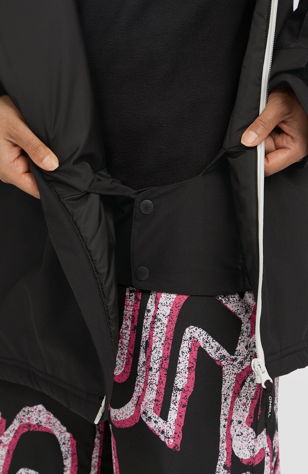 Nahaufnahme des geschlossenen Schneefangs der schwarzen FWC'Play Asymmetric Ski- und Snowboardjacke für Damen
