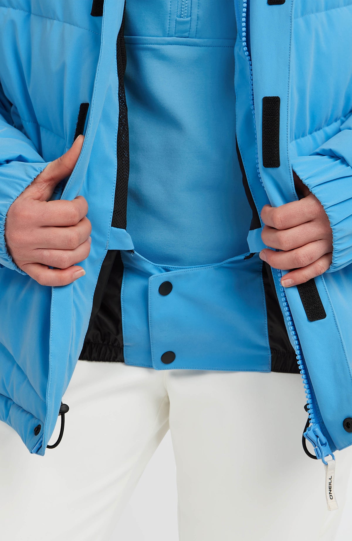 Nahaufnahme des integrierten Schneefangs der blauen Gesteppten FWC'Cruz Hybrid-Skijacke