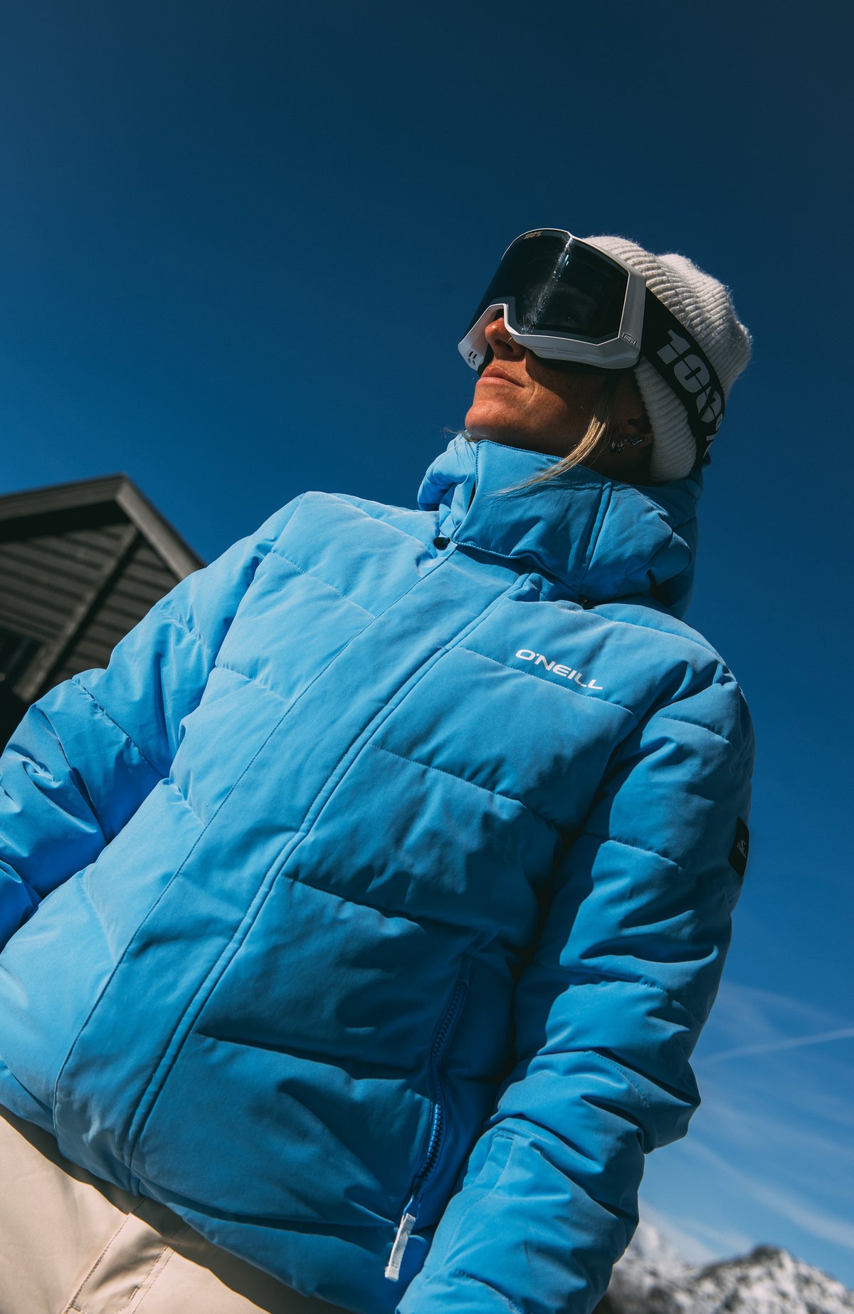 Gesteppte FWC'Cruz Hybrid-Skijacke in Blau im Schnee, von unten fotografiert am Model