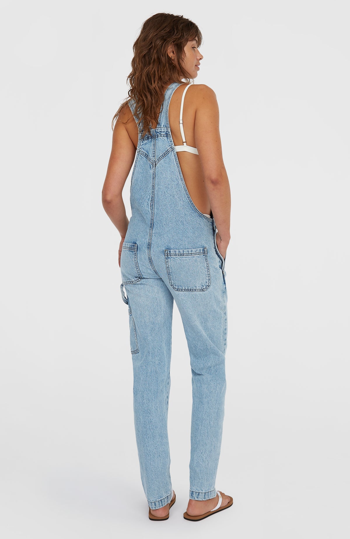 Blaue Essentials Twill-Latzhose für Damen, getragen am Model, Rückansicht mit aufgesetzten Taschen