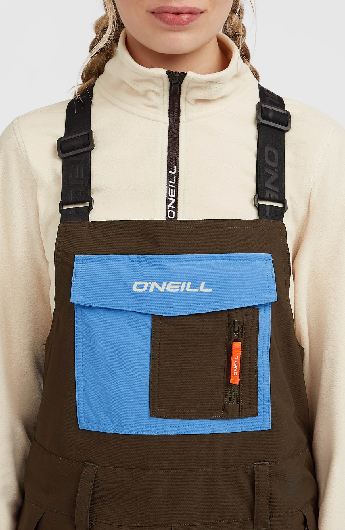 FWC'Peak Bib Skihose für Damen, braun, Nahaufnahme am Model vom Latz mit blauer Tasche und Logo-Schriftzug