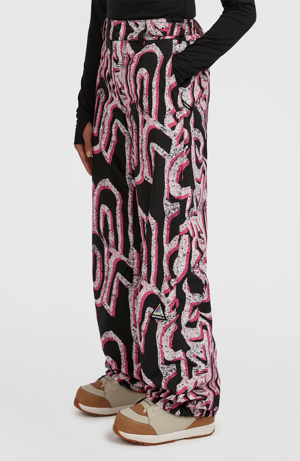FWC'Play Ski- und Snowboardhose, weiß mit Grafikmuster in Schwarz und Pink, Halbprofilansicht am Model mit Logo-Patch
