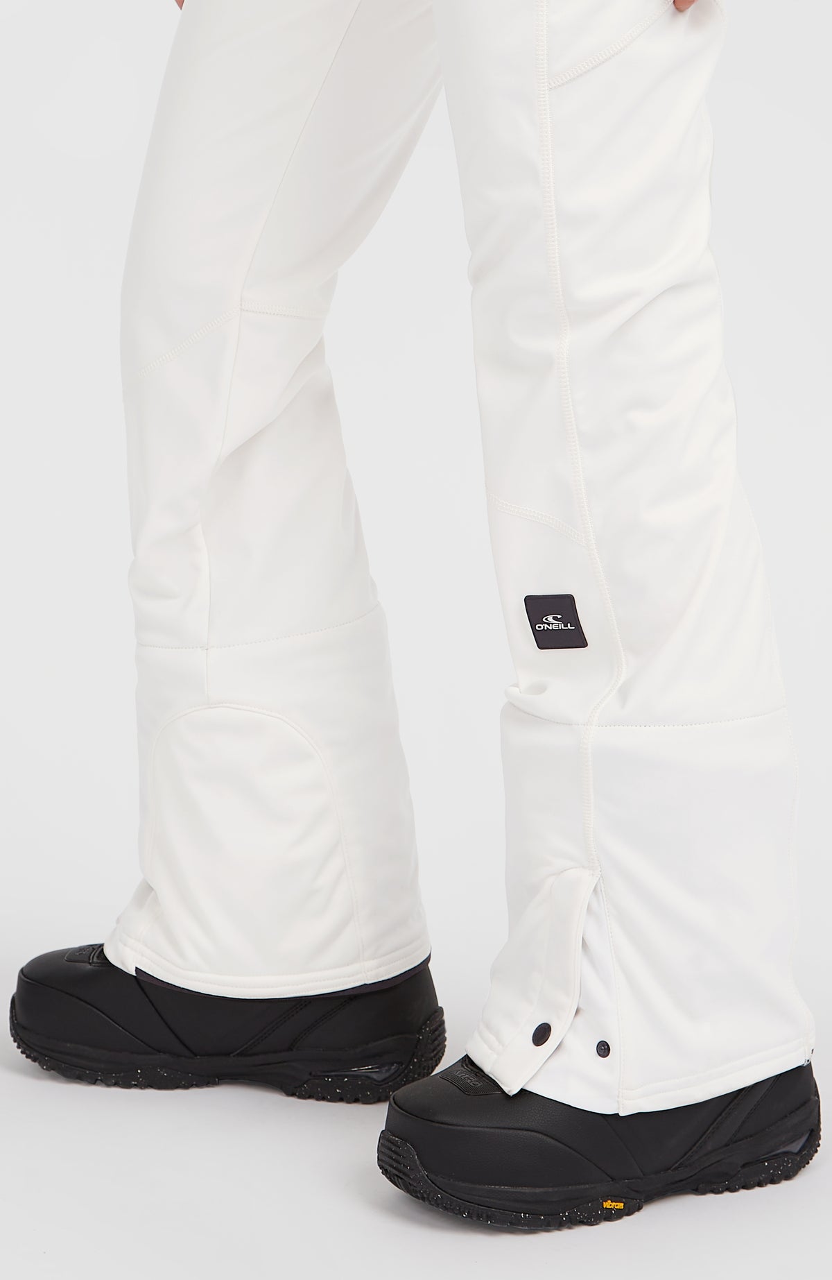 FWC'Cruz Softshell-Skihose, weiß, Nahaufnahme des Hosenbeins mit Logo-Badge und Knöpfen am Saum