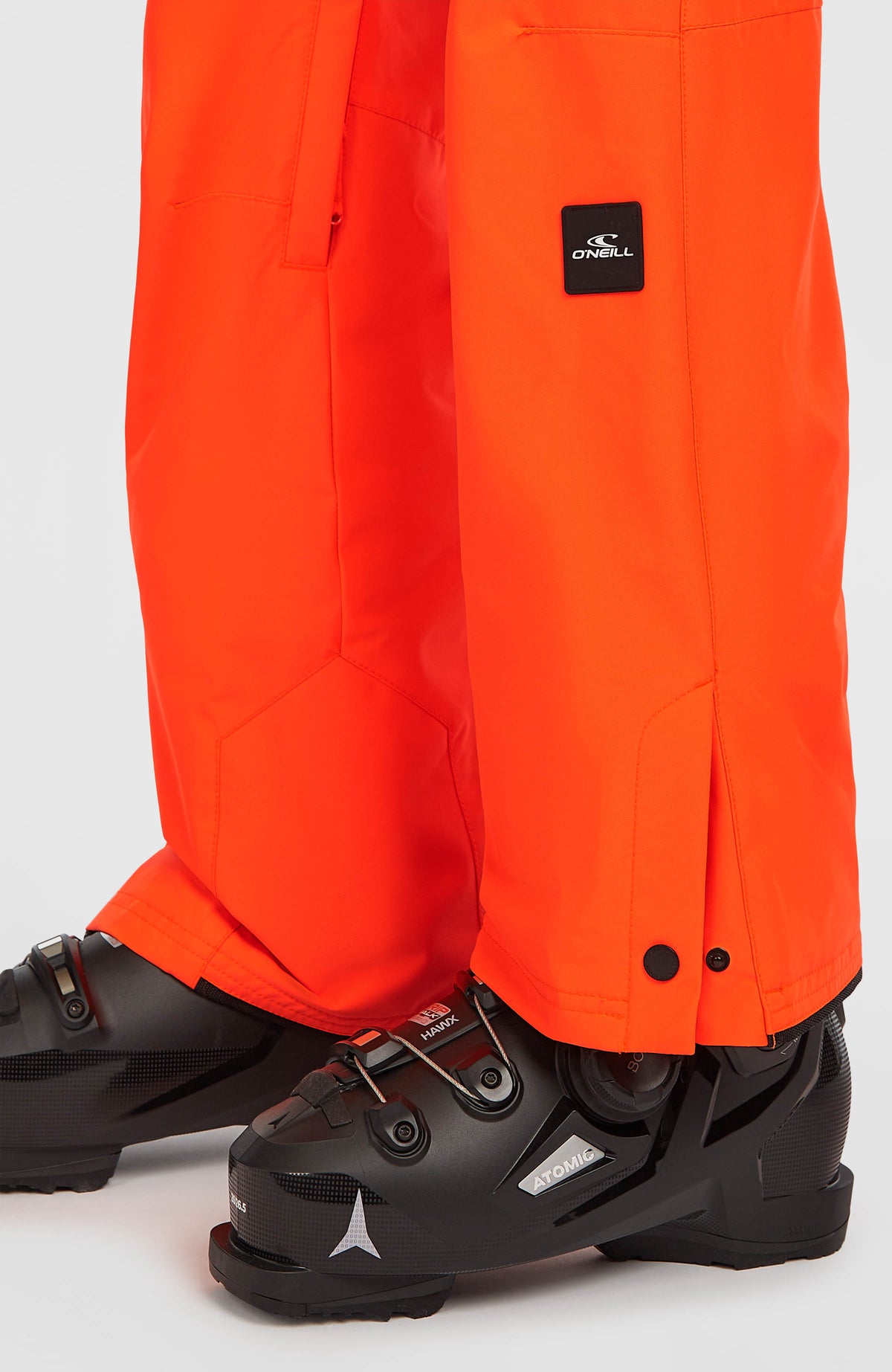Nahaufnahme vom Saum der roten FWC'Cruz Slim Skihose am Model mit Druckknopfverschluss
