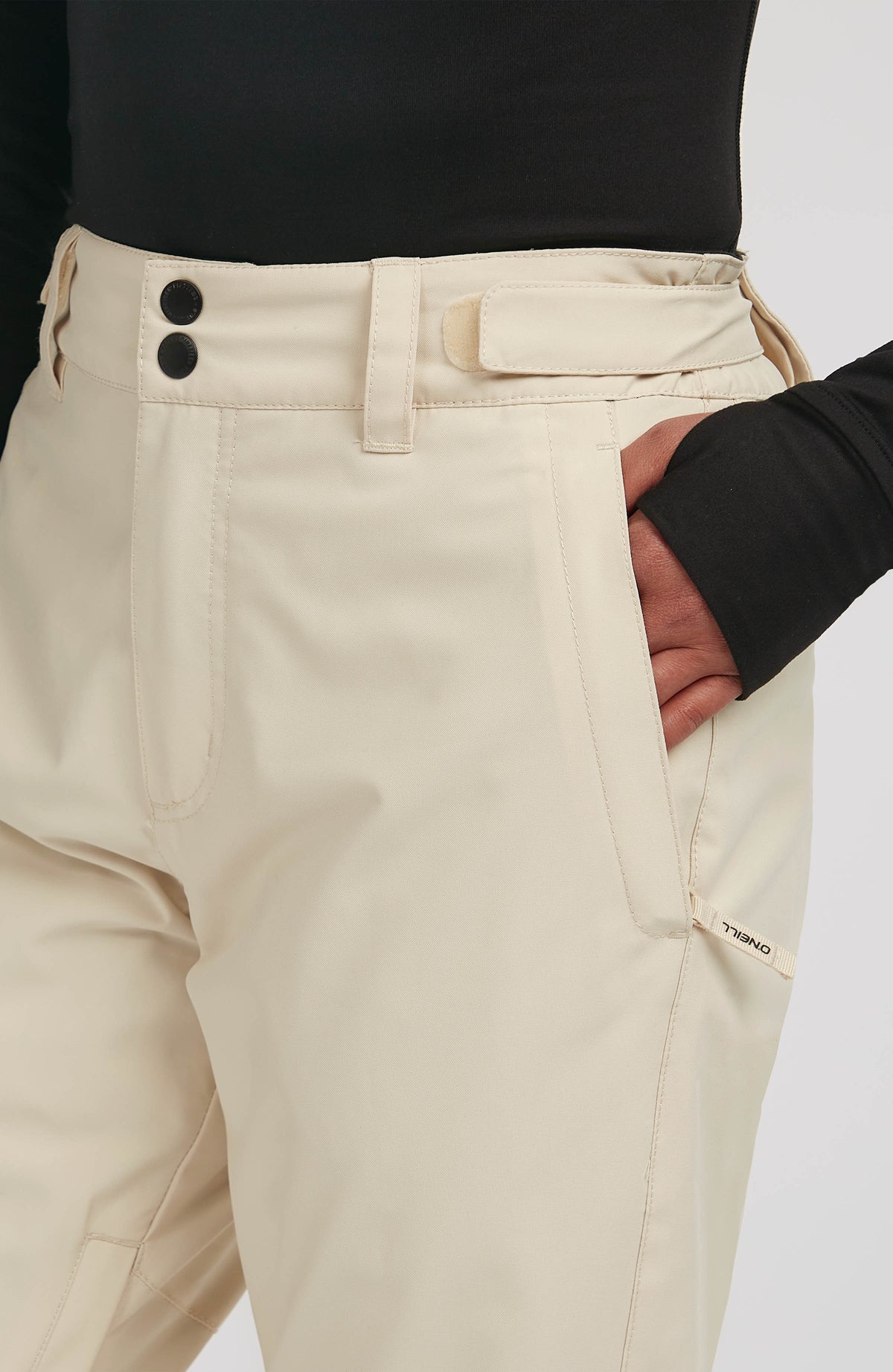Nahaufnahme von Bund, Druckknöpfen und Reißverschlusstasche der beigen FWC'Cruz Slim Skihose