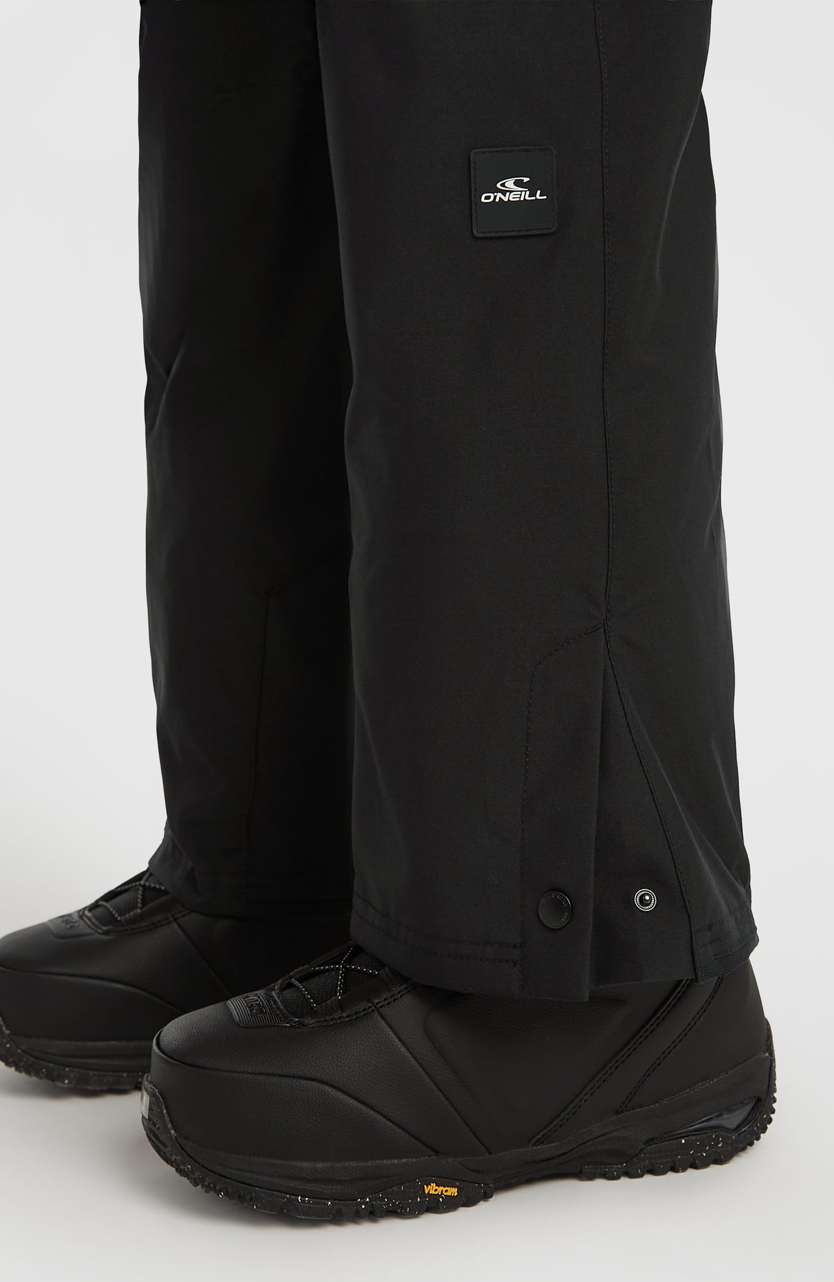 FWC'Cruz Slim Skihose, schwarz, Nahaufnahme des Hosenbeinsaums mit Druckknopf und Logo-Badge
