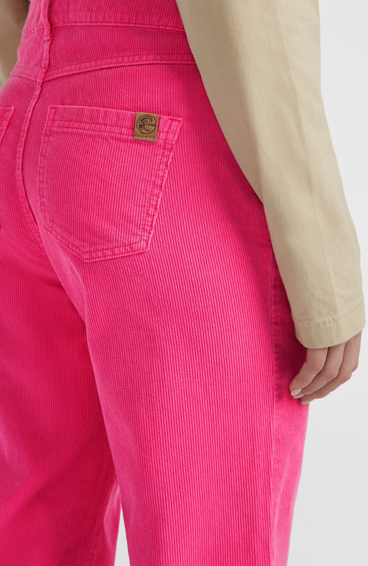 Nahaufnahme der Gesäßtasche mit Logo-Patch der pinken O'Riginals Cord-Latzhose am Model