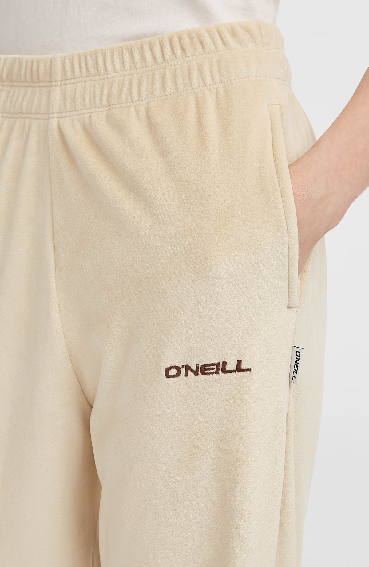 Nahaufnahme der beigen FWC'Cruz Velour Jogginghose mit Seitentasche und Logo-Stickerei