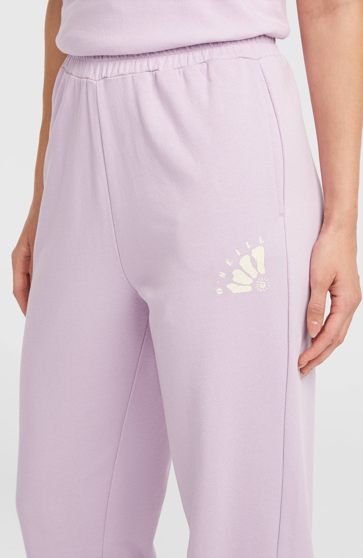 Nahaufnahme der lila Women of the Wave Jogginghose für Damen, Logo-Print in Gelb neben der Eingrifftasche