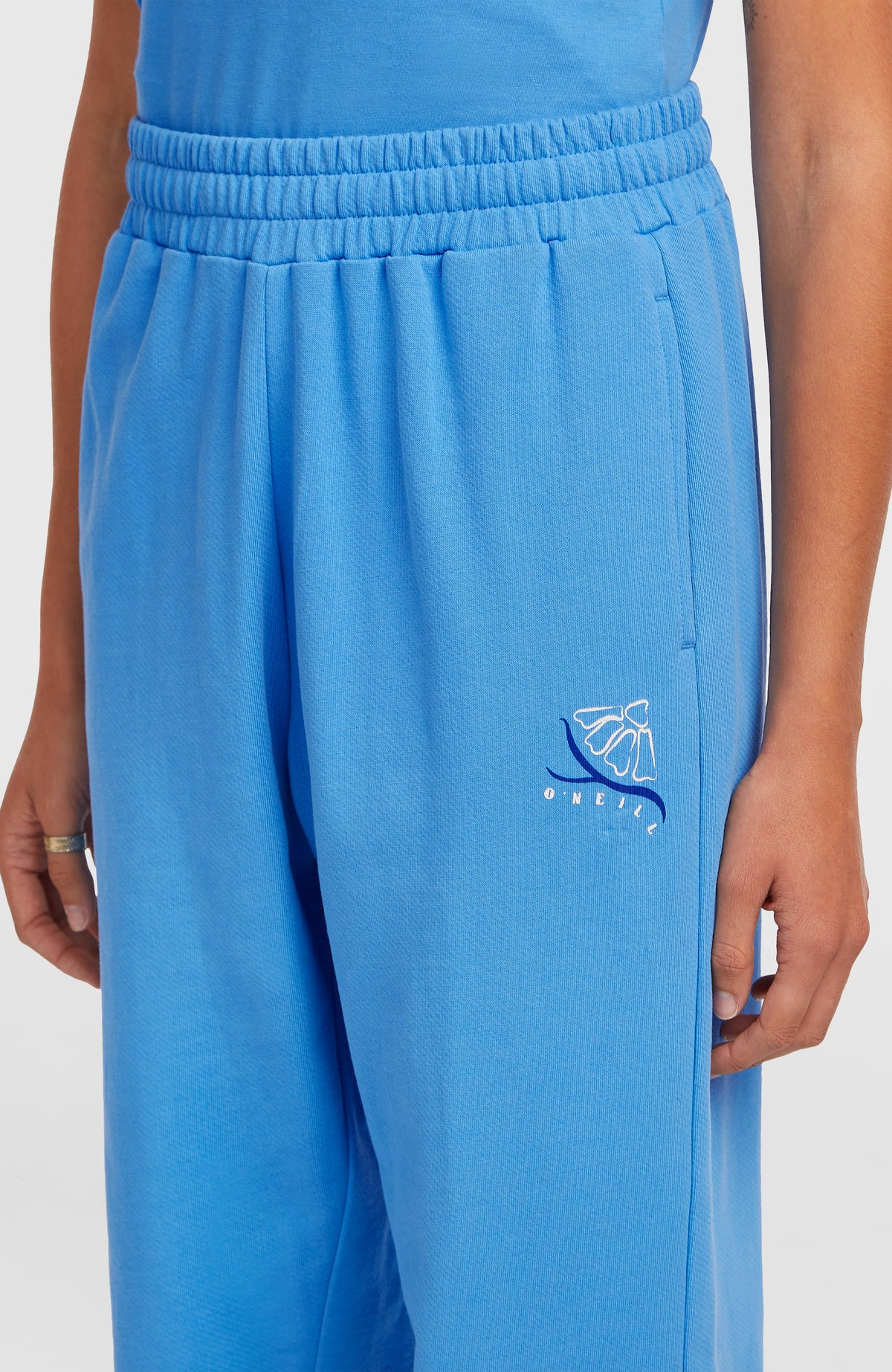 Nahaufnahme der blauen Women of the Wave Jogginghose am Model, elastischer Bund und Logo-Print