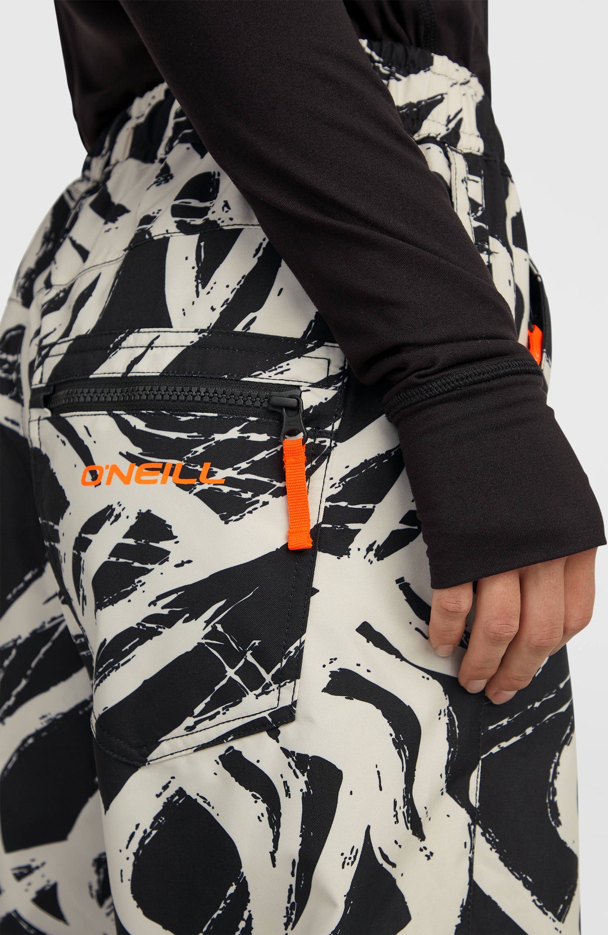 Nahaufnahme der Reißverschlusstasche mit Logo-Schriftzug der weißen FWC Oversized Ski- und Snowboardhose am Model