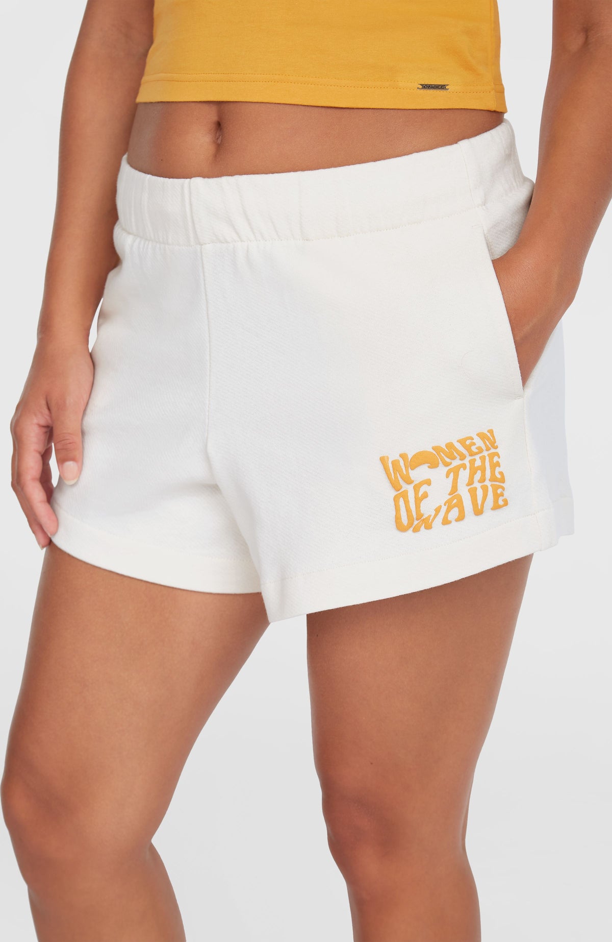 Women of the Wave Sweatshorts, beige, Nahaufnahme am Model mit Fokus auf Eingrifftasche und Logo-Print