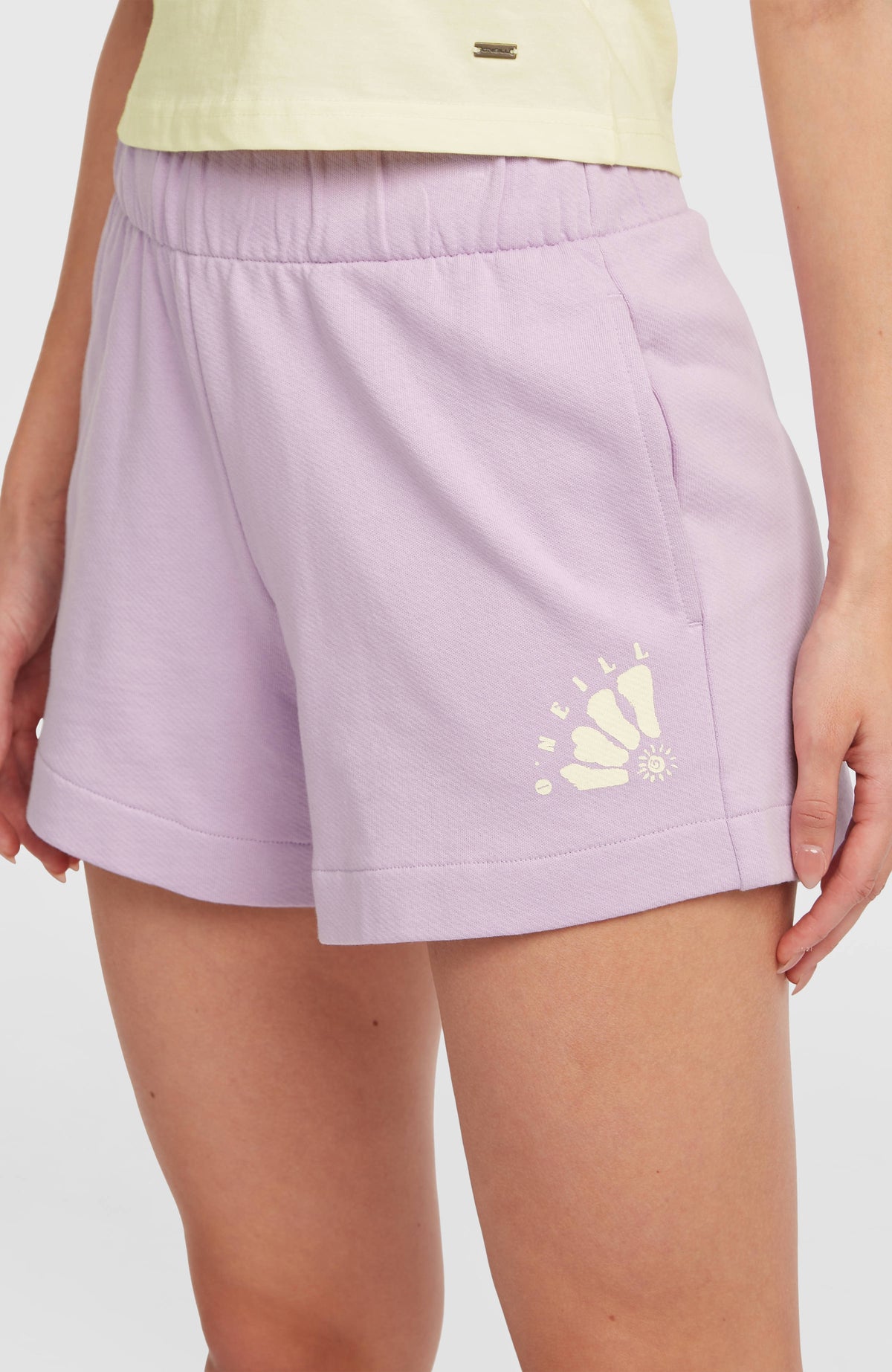 Nahaufnahme der lila Women of the Wave Sweatshorts am Model mit Seitentasche und elastischem Bund