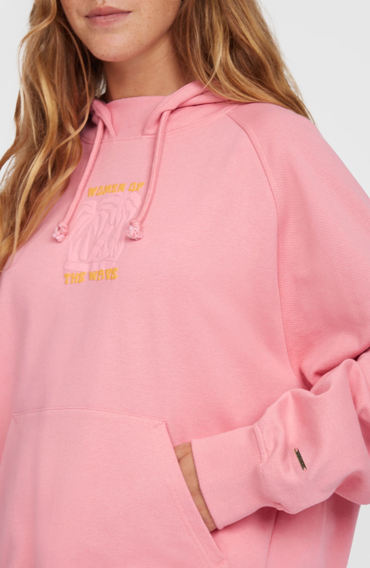 Nahaufnahme des Women of the Wave Hoodie in Pink mit gelbem Grafik-Print auf der Brust und Kordelzug am Kragen