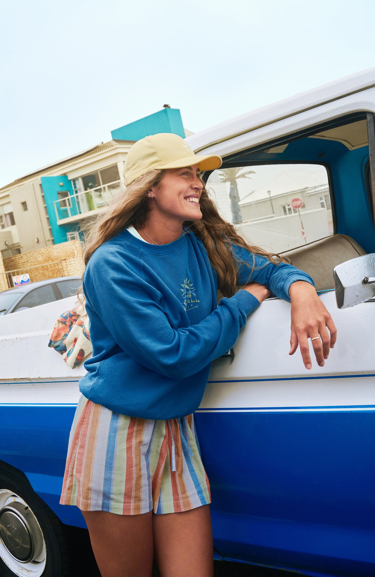 Beach Vintage Crew Sweatshirt für Damen, blau mit Logo-Print, getragen am Model an einem Auto