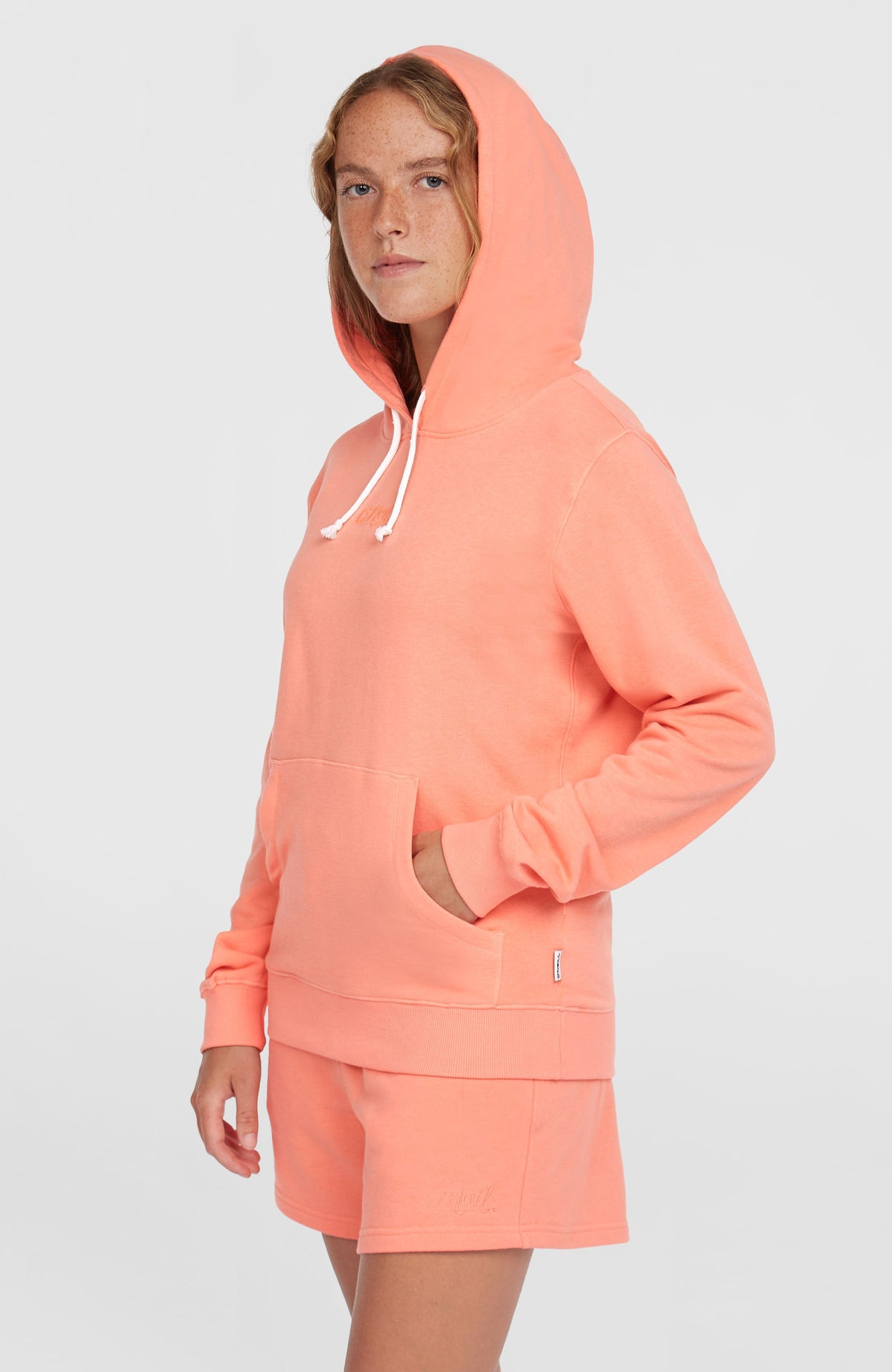 Essentials O'Neill Script Hoodie für Damen, pink, Seitenansicht am Model mit aufgesetzter Kapuze und Tasche