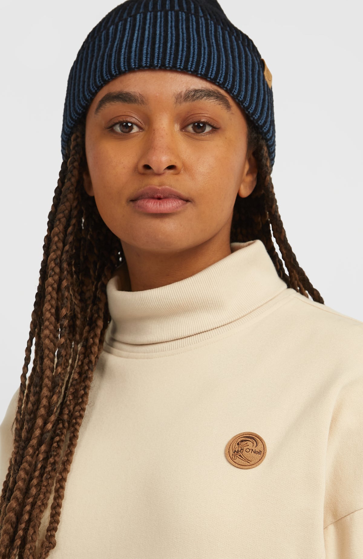 Nahaufnahme des gerippten Stehkragens und Logo-Patches am beigen O'Riginals Crew Sweatshirt für Damen