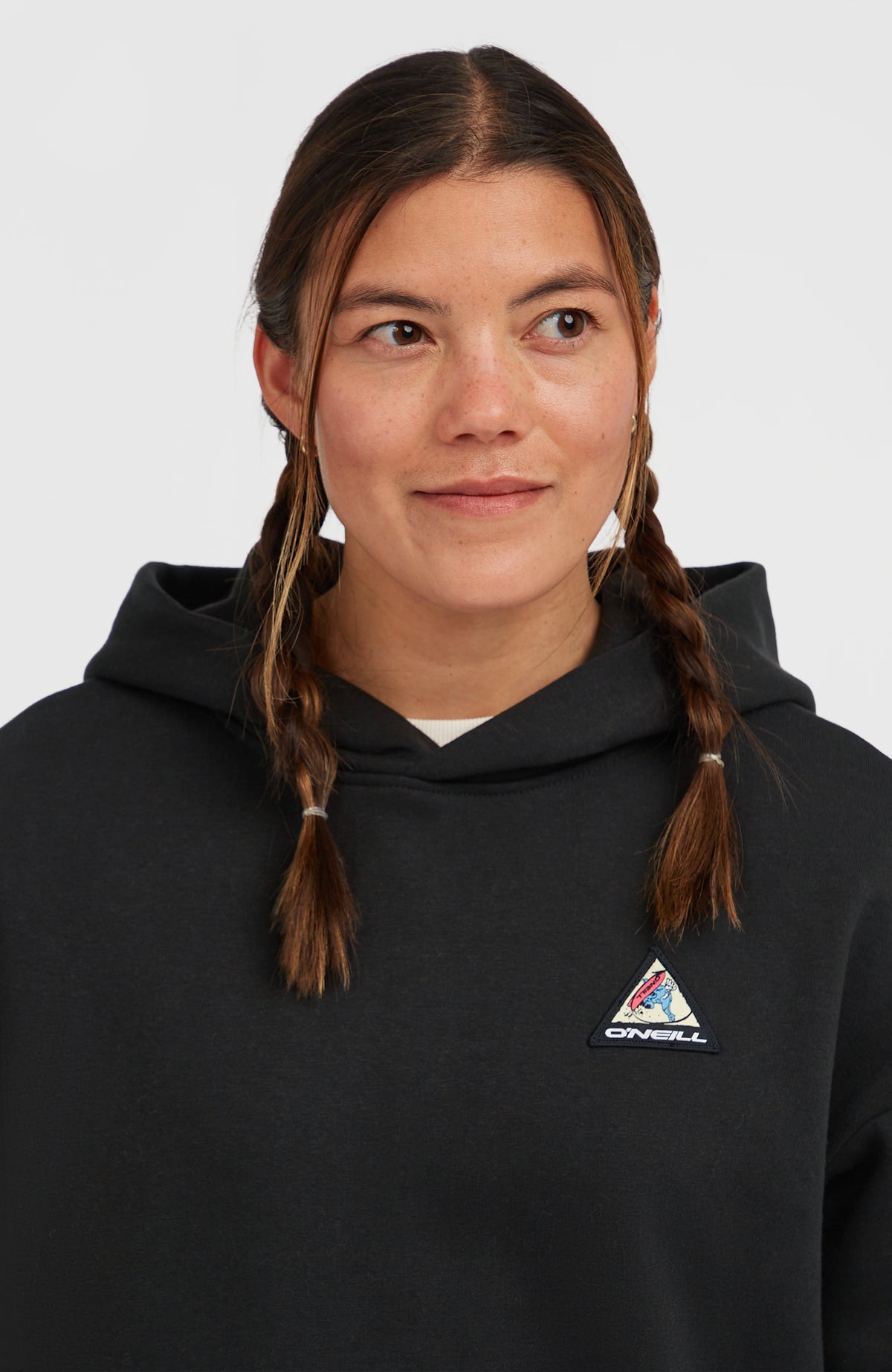 FWC'Play Hoodie für Damen, schwarz, Nahaufnahme am Model mit Fokus auf den dreieckigen Logo-Patch