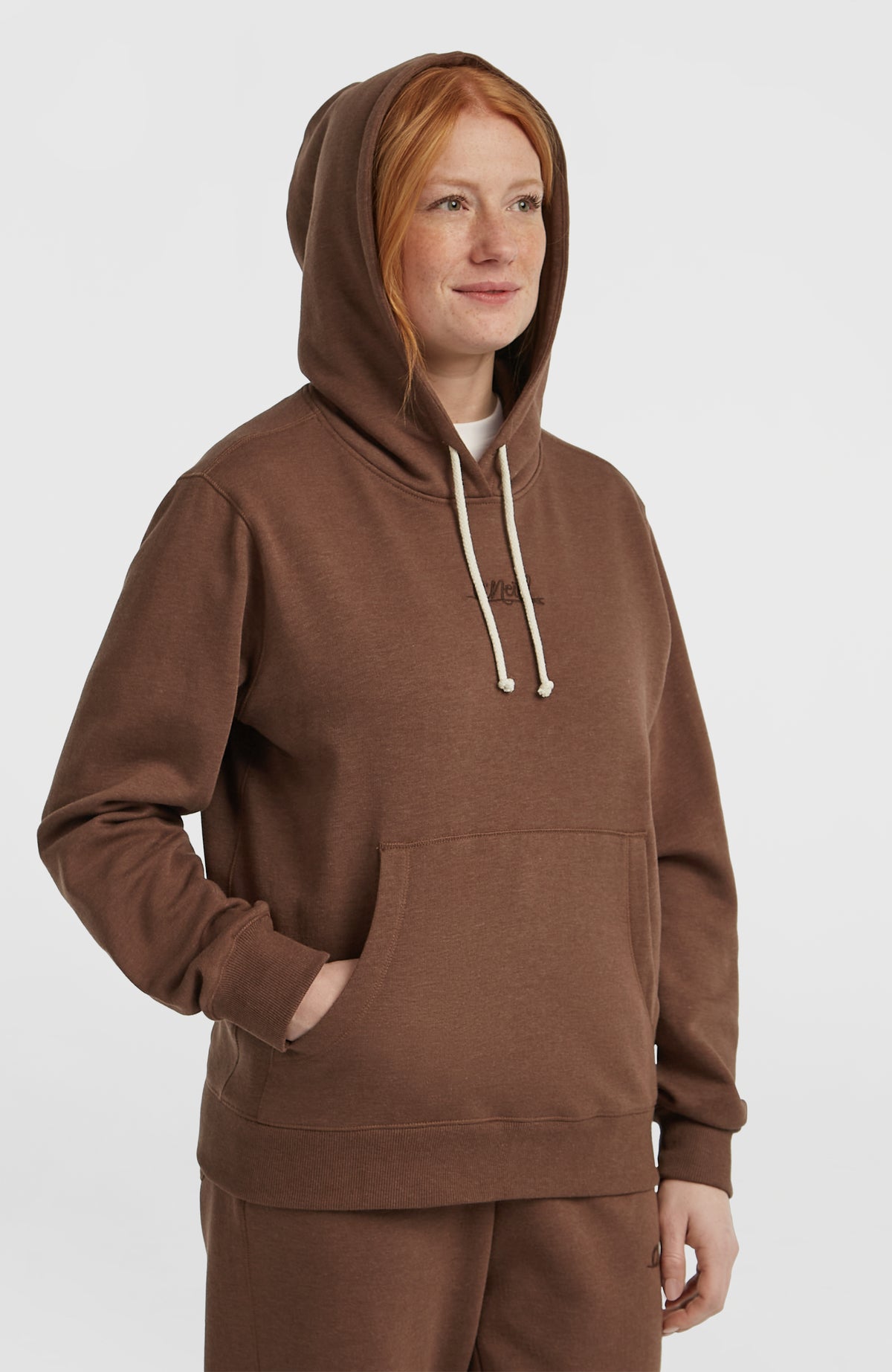 Essentials Script Hoodie für Damen in Braun, Halbprofil am Model mit aufgesetzter Kapuze