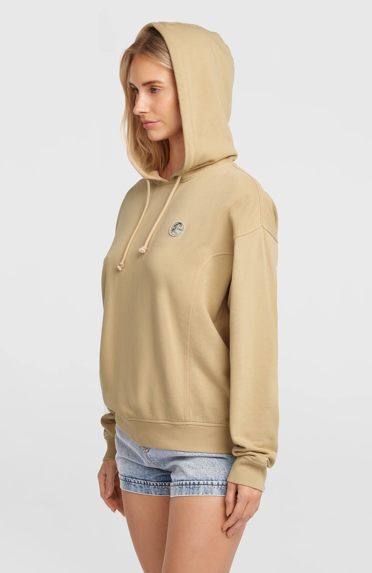 O'Riginals Hoodie für Damen, beige, Seitenansicht am Model mit aufgesetzter Kapuze und rundem Logo-Badge