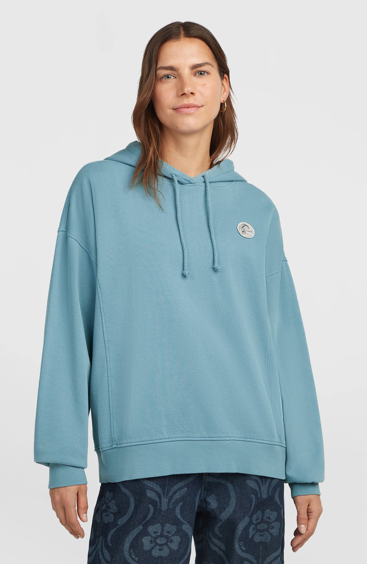 O'Riginals Badge Hoodie für Damen, blau, Vorderansicht am Model mit rundem Logo-Badge auf der Brust