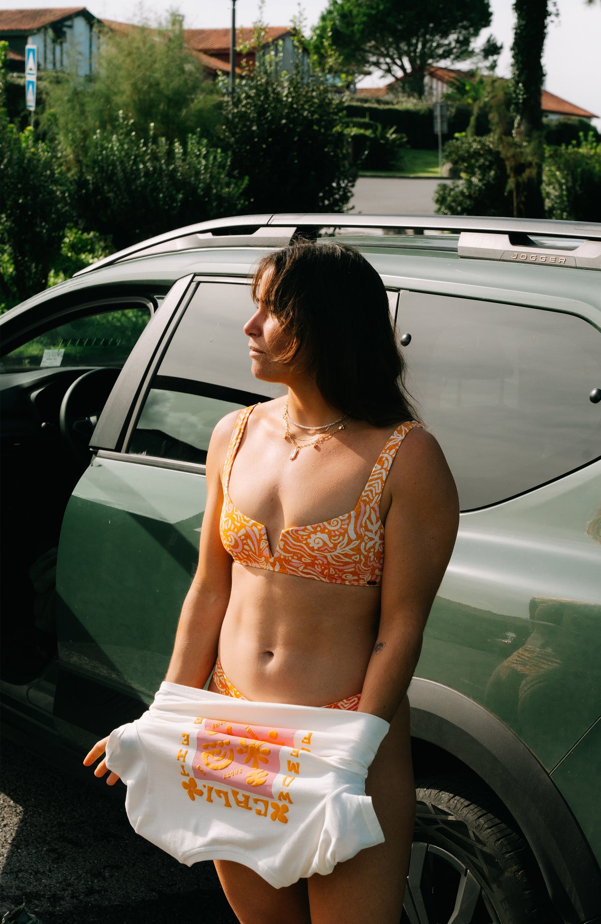 Women Of Bikini-Set, orange mit Wellenmuster in Weiß und Rosa, getragen am Model am Auto