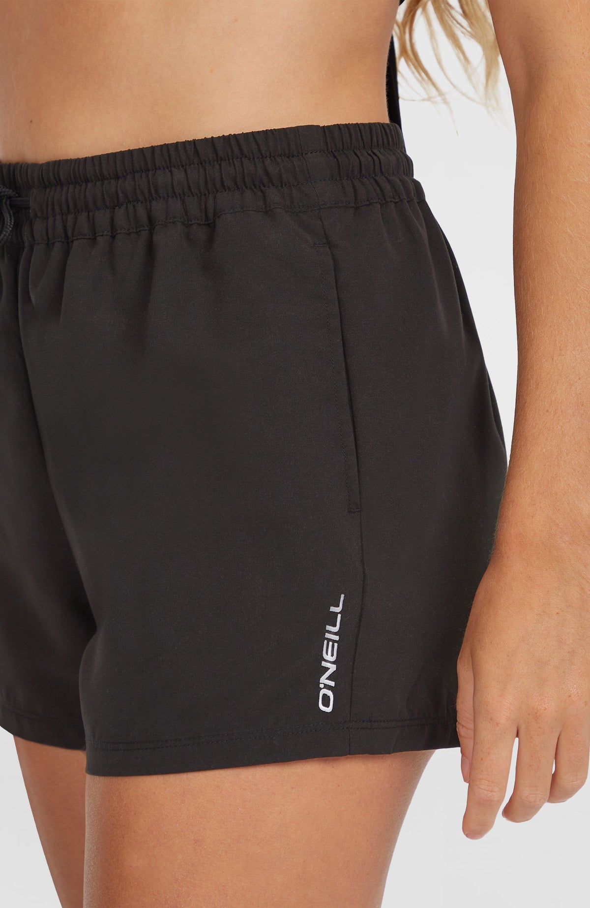 Essentials 12'' Badeshorts für Damen, schwarz, Nahaufnahme der Seitentasche mit weißem Logo-Print