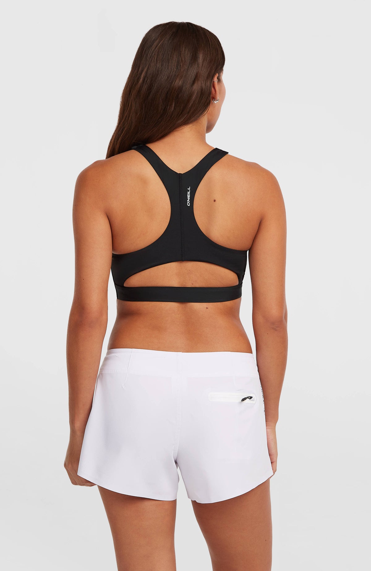 Surftop für Damen, schwarz, Rückansicht am Model, sportlicher Ringerrücken und Cut-Out über dem Bund