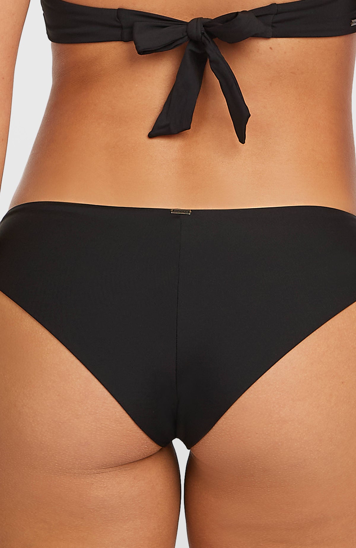 Nahaufnahme der schwarzen Maoi Bikinihose von hinten am Model mit kleinem Metall-Logo am Bund