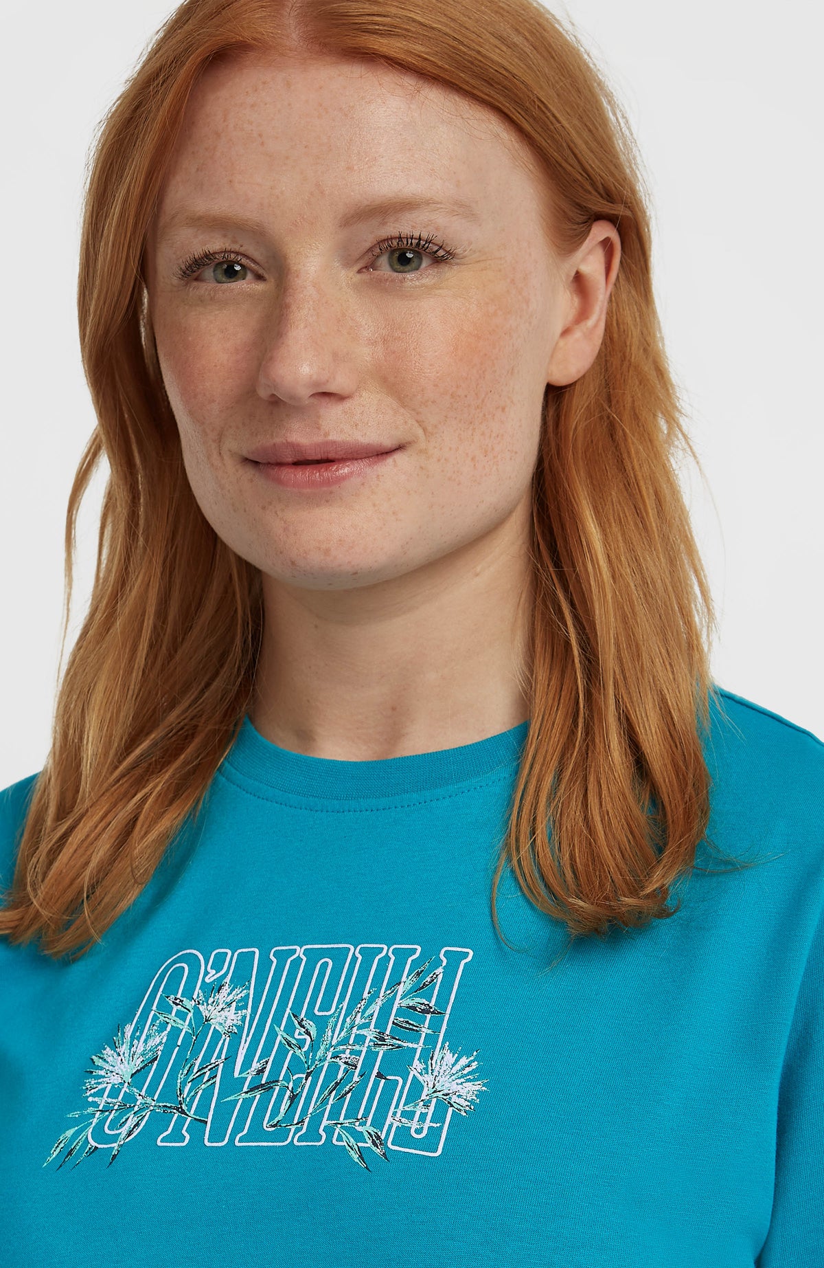 Graphic T-Shirt, blau mit Logo-Print in Weiß und Grün, Nahaufnahme des Rundhalsausschnitts am Model
