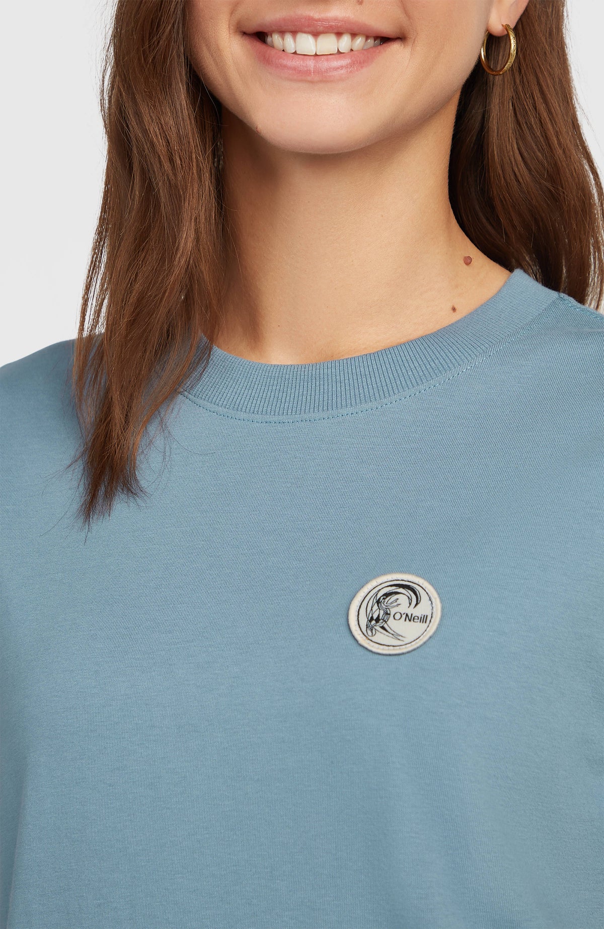 Nahaufnahme des gerippten Kragens und Logo-Badges am blauen O'Riginals Badge T-Shirt