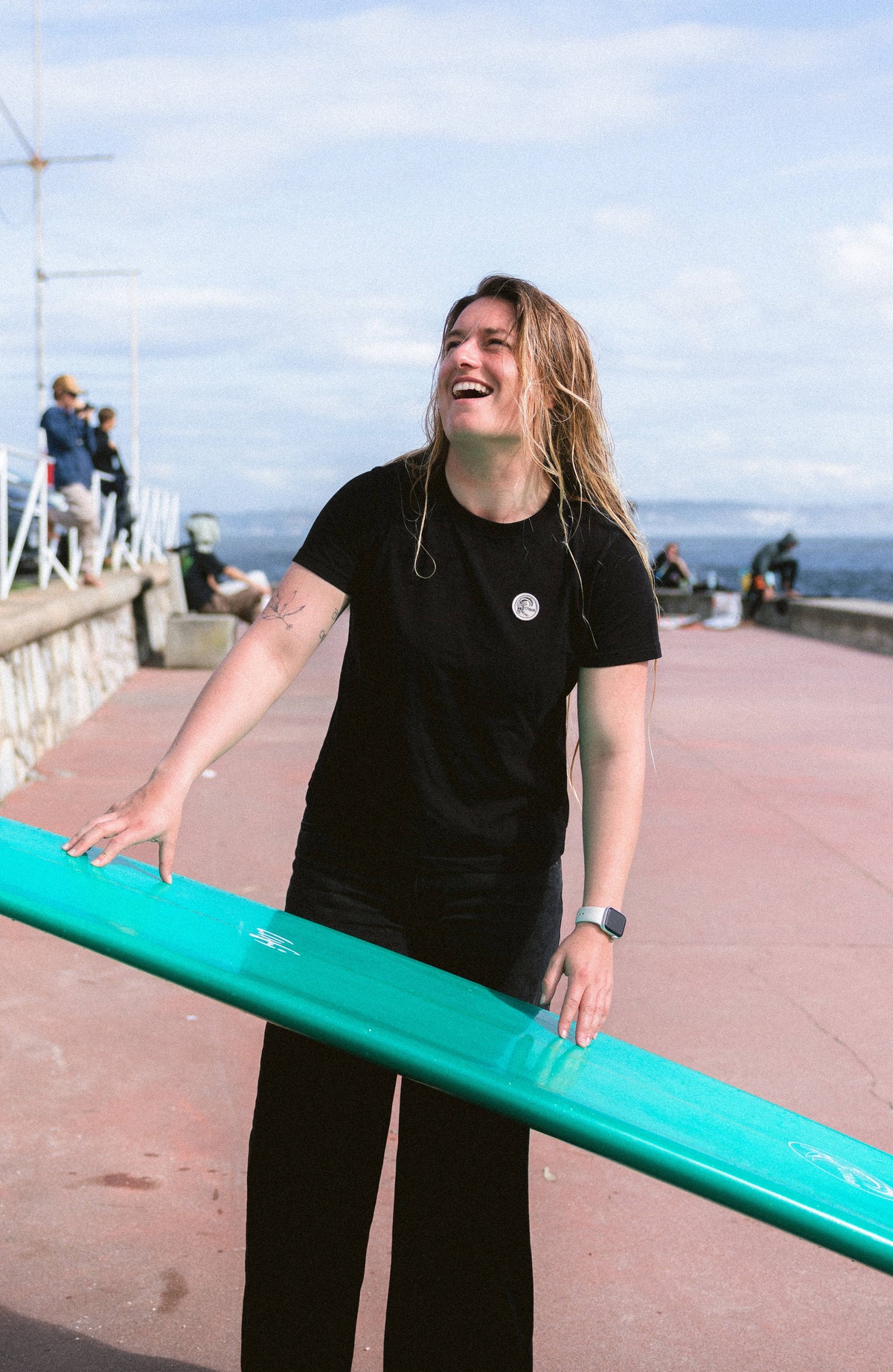 O'Neill O'Riginals Badge T-Shirt für Damen, schwarz, getragen am Model an der Uferpromenade am Meer