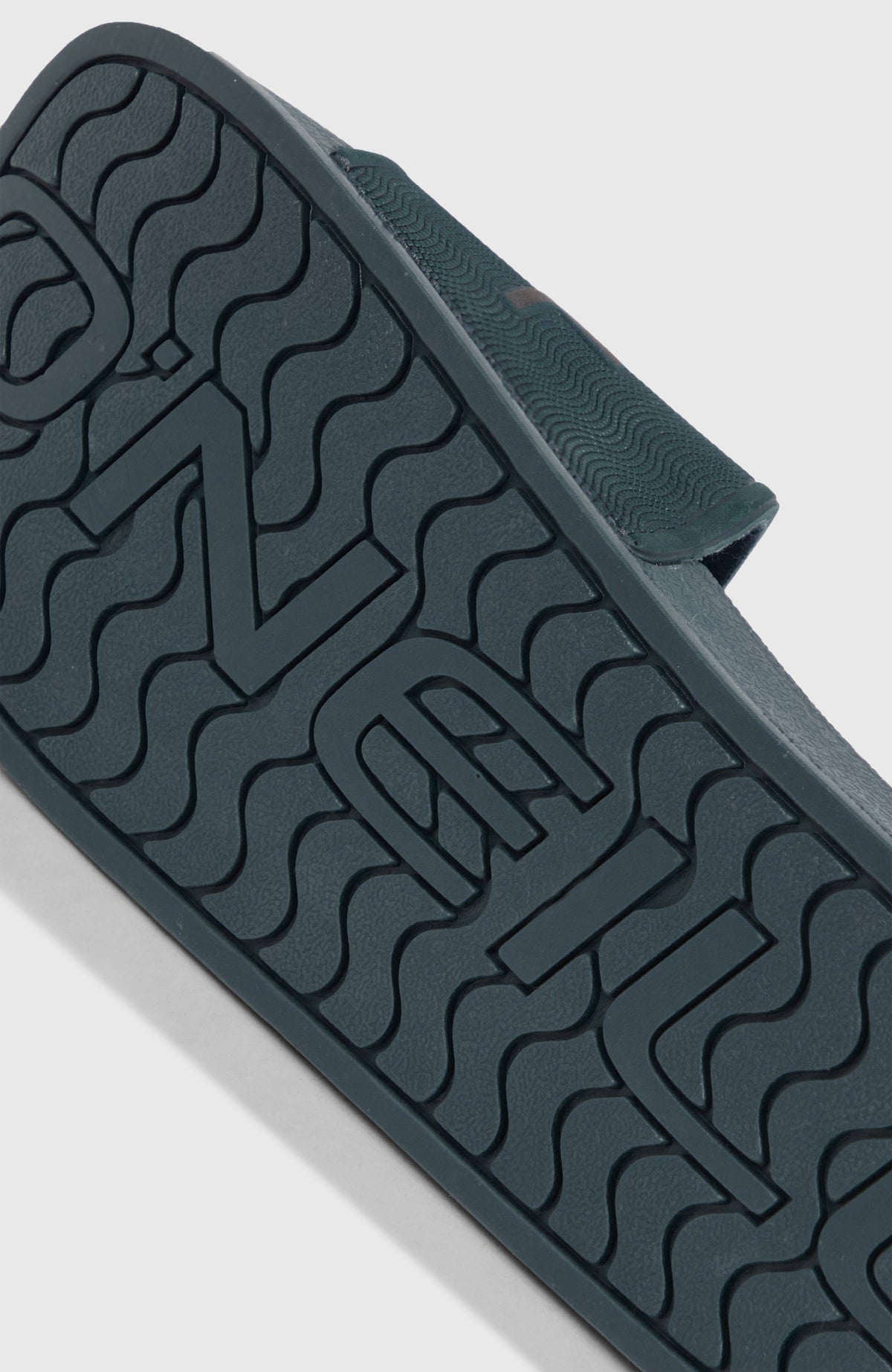 Nahaufnahme der strukturierten Sohle der blauen Logo Slides für Herren mit Logo-Prägung