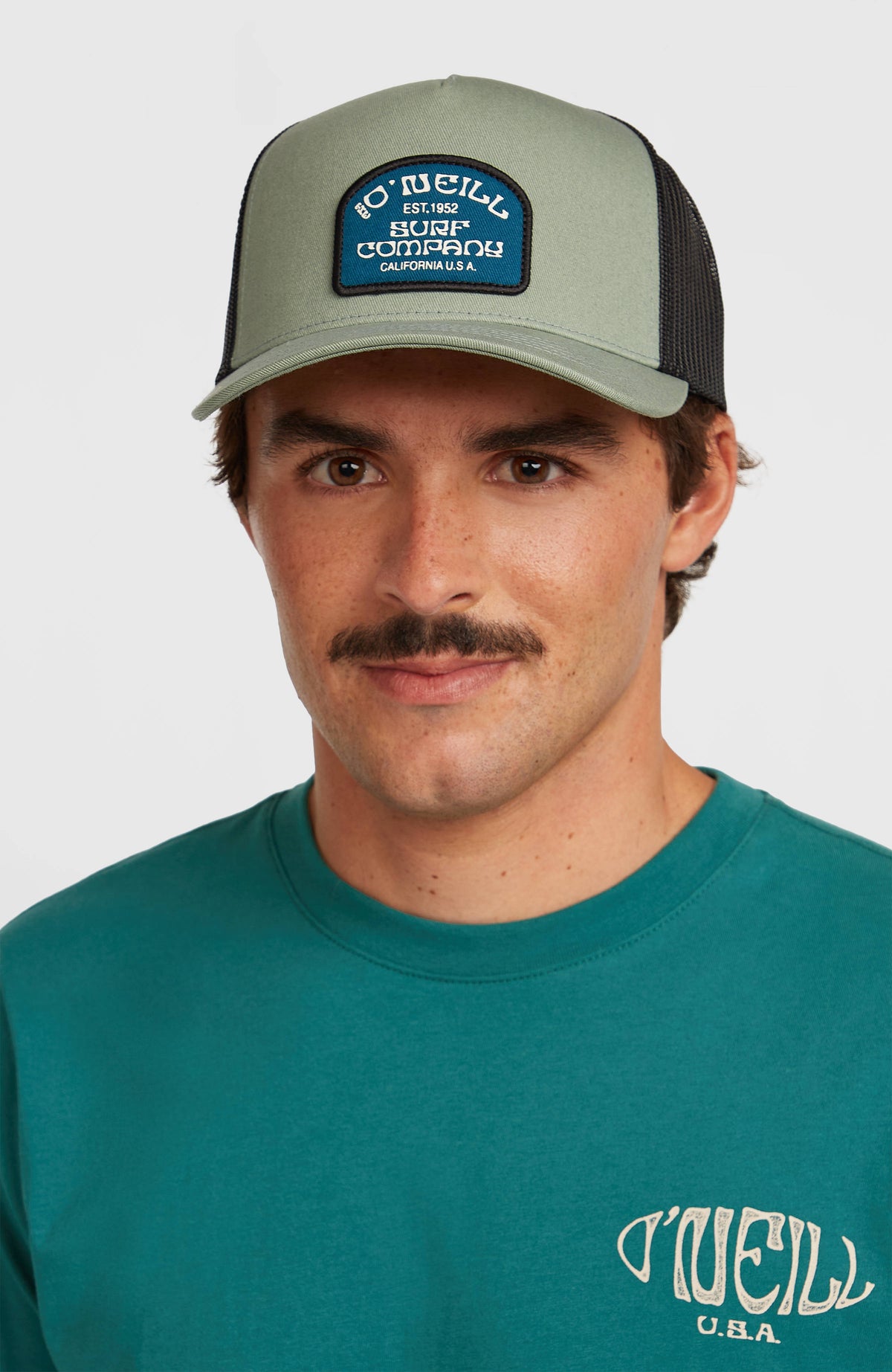 Grüne Retro Trucker Cap für Herren, getragen am Model, Vorderansicht mit Logo-Patch auf der Front