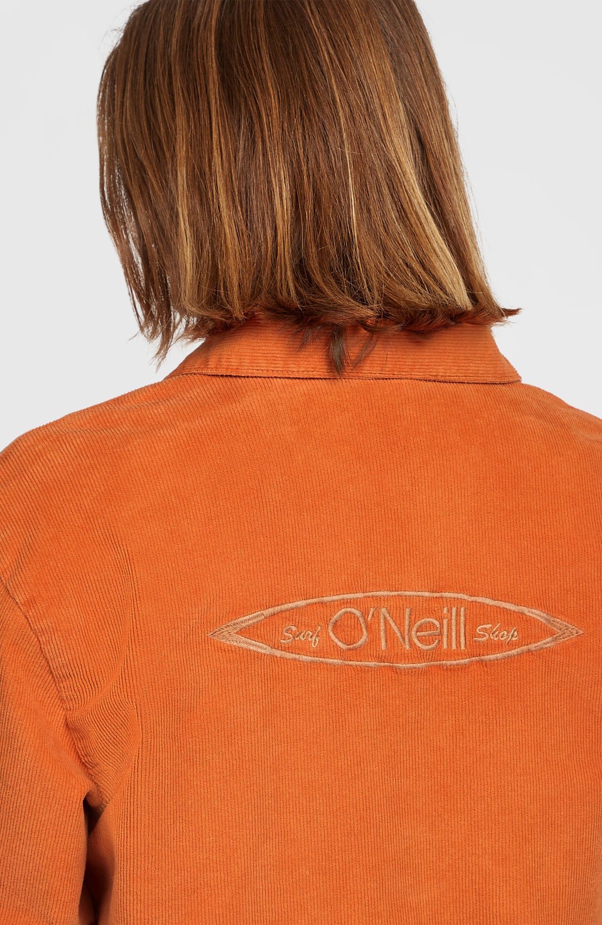 Nahaufnahme der orangefarbenen Cord Coach Jacke mit gesticktem Schriftzug am Rücken