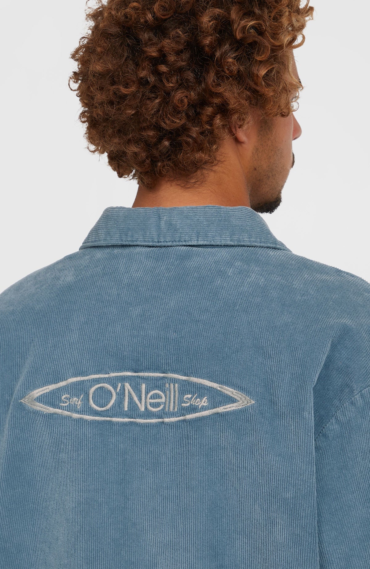Nahaufnahme der blauen Cord Coach Jacke von hinten mit gesticktem Logo auf der Rückseite