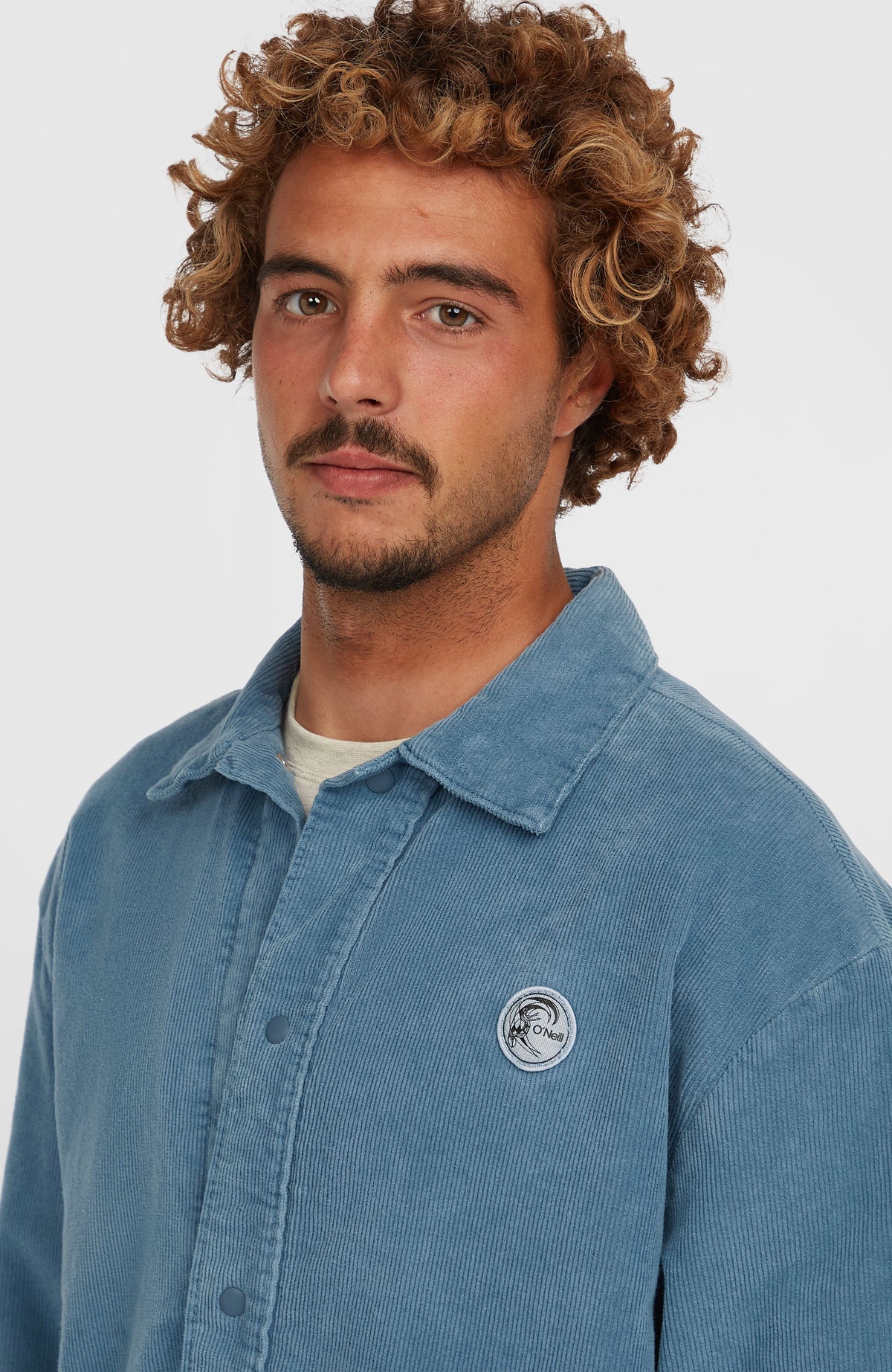 Nahaufnahme der blauen Cord Coach Jacke mit Kragen und rundem Logo-Patch