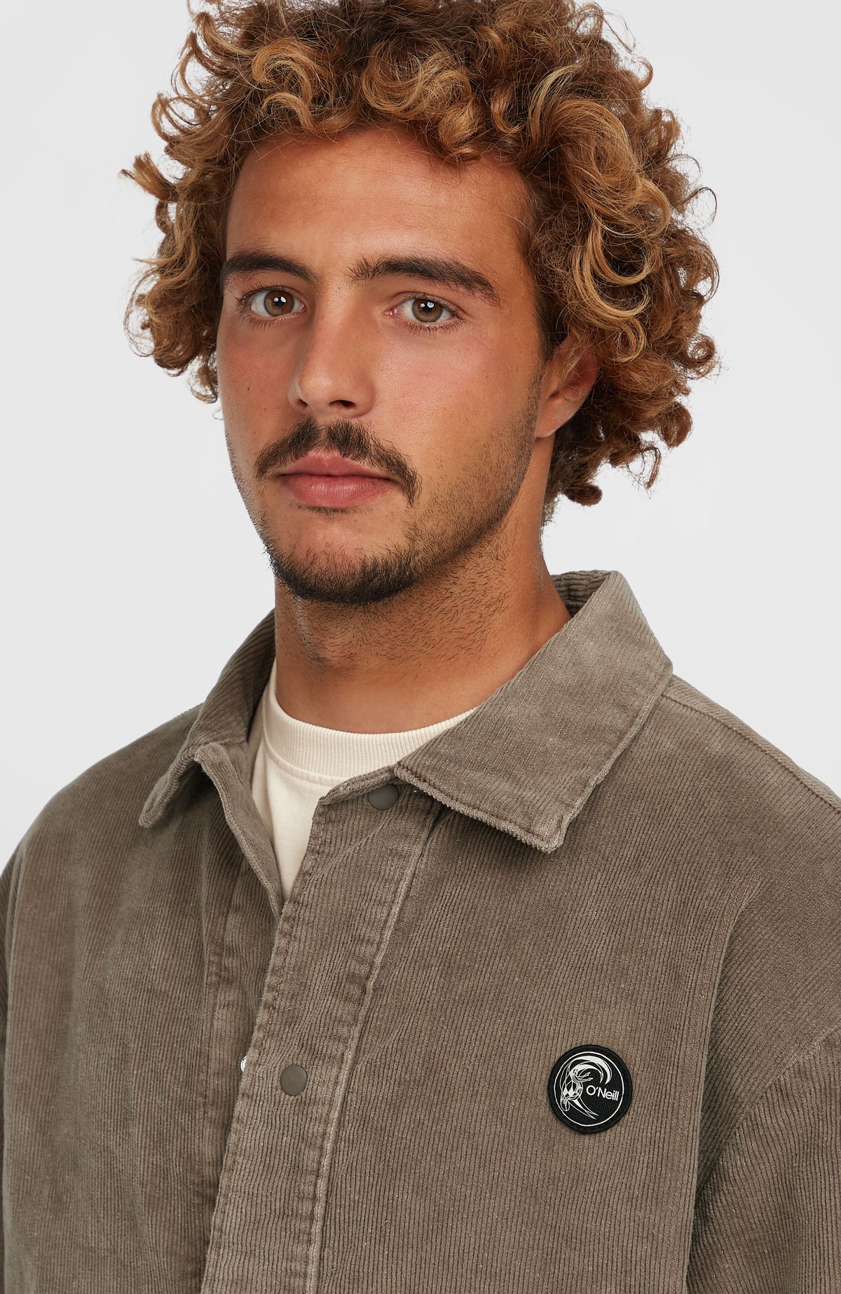 Nahaufnahme von Kragen und Logo-Patch der braunen Cord Coach Jacke für Herren