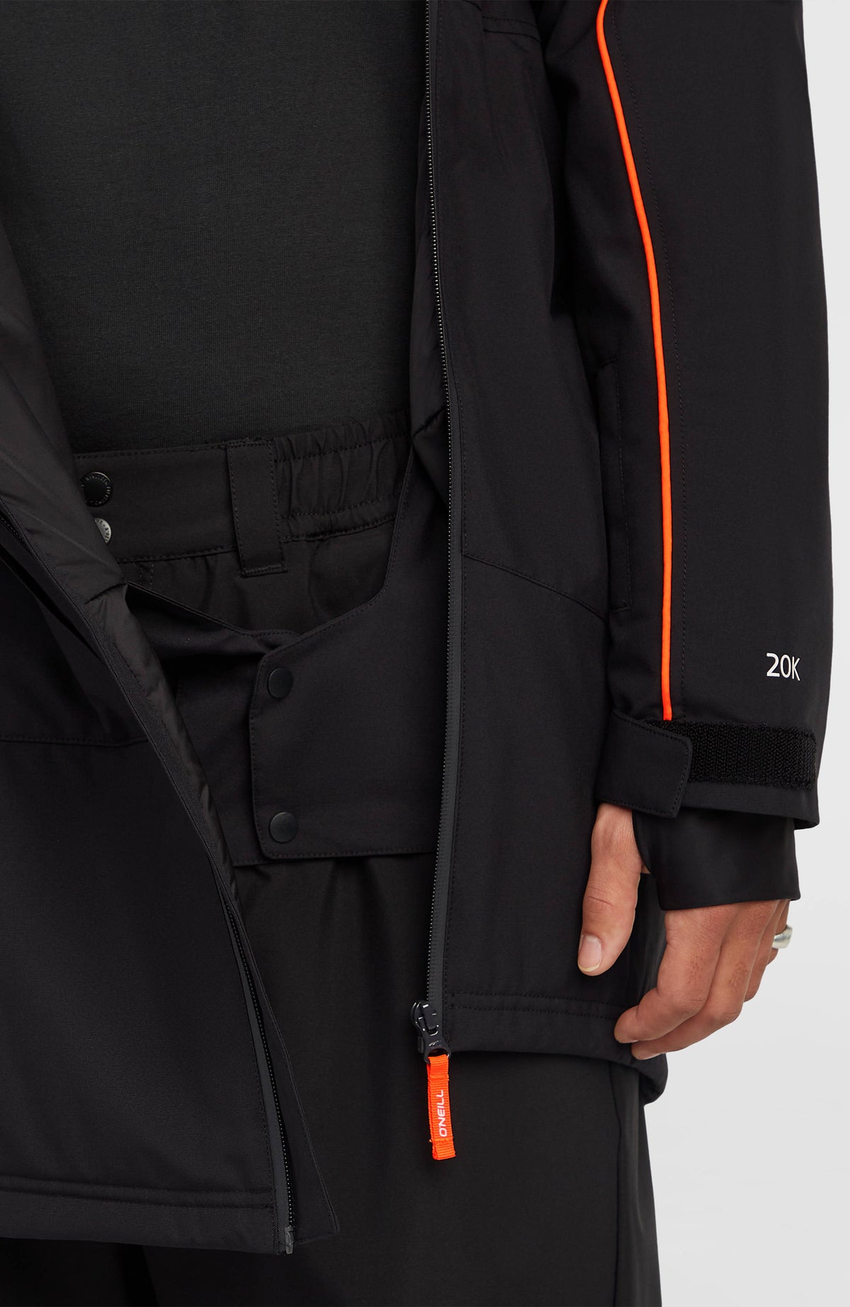 Nahaufnahme von unterem Saum, Reißverschluss und Schneefang der schwarzen FWC'Play Asymmetric Ski- und Snowboardjacke