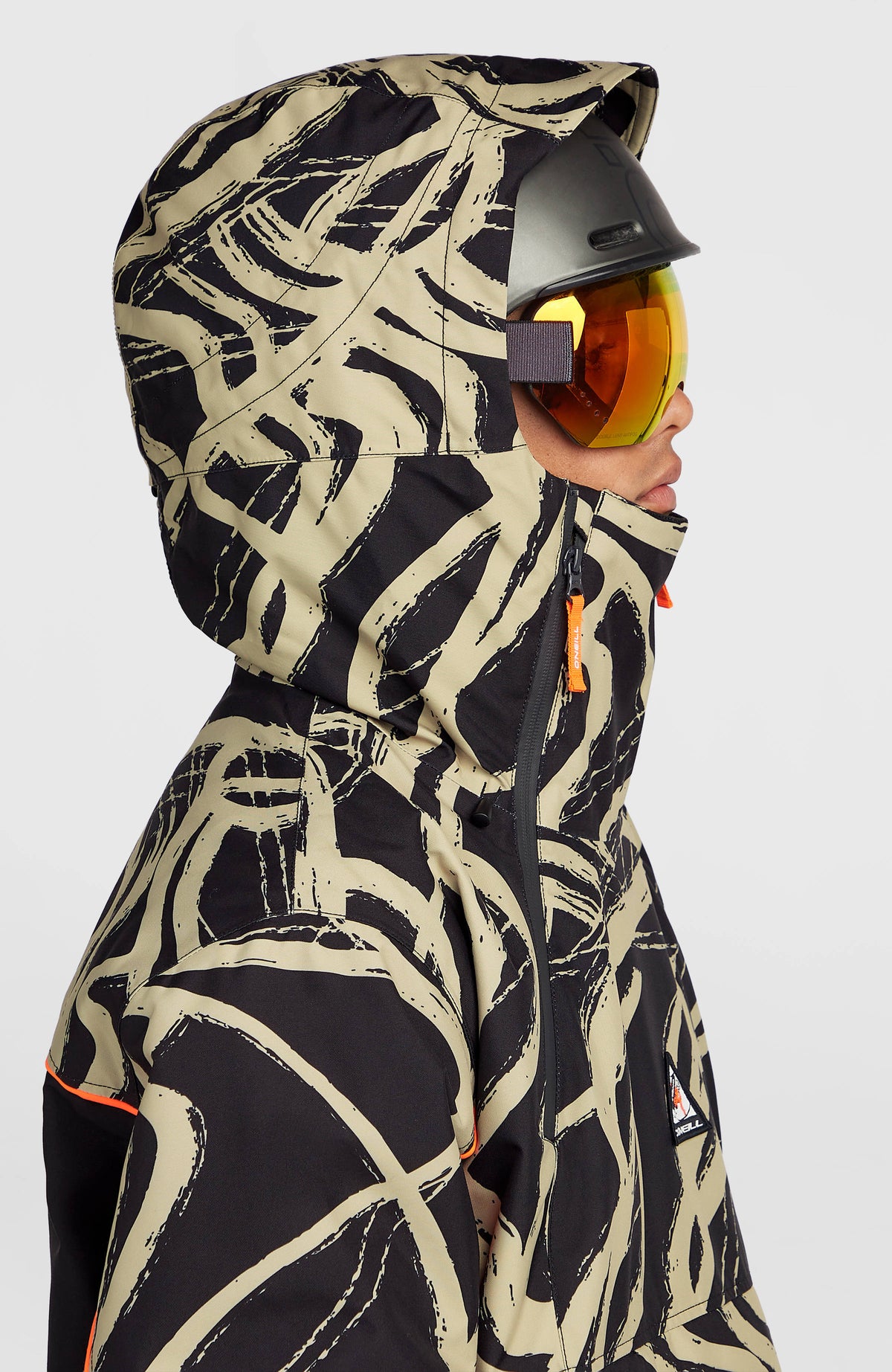 Nahaufnahme der Kapuze und des hohen Kragens der beigen FWC'Play Asymmetric Ski- und Snowboardjacke am Model