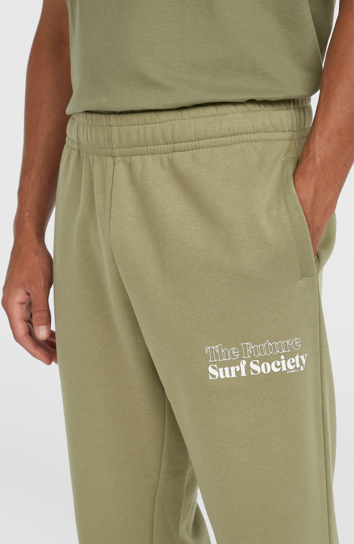 Nahaufnahme der grünen Future Surf Society Jogginghose am Model mit Seitentasche und Logo-Print