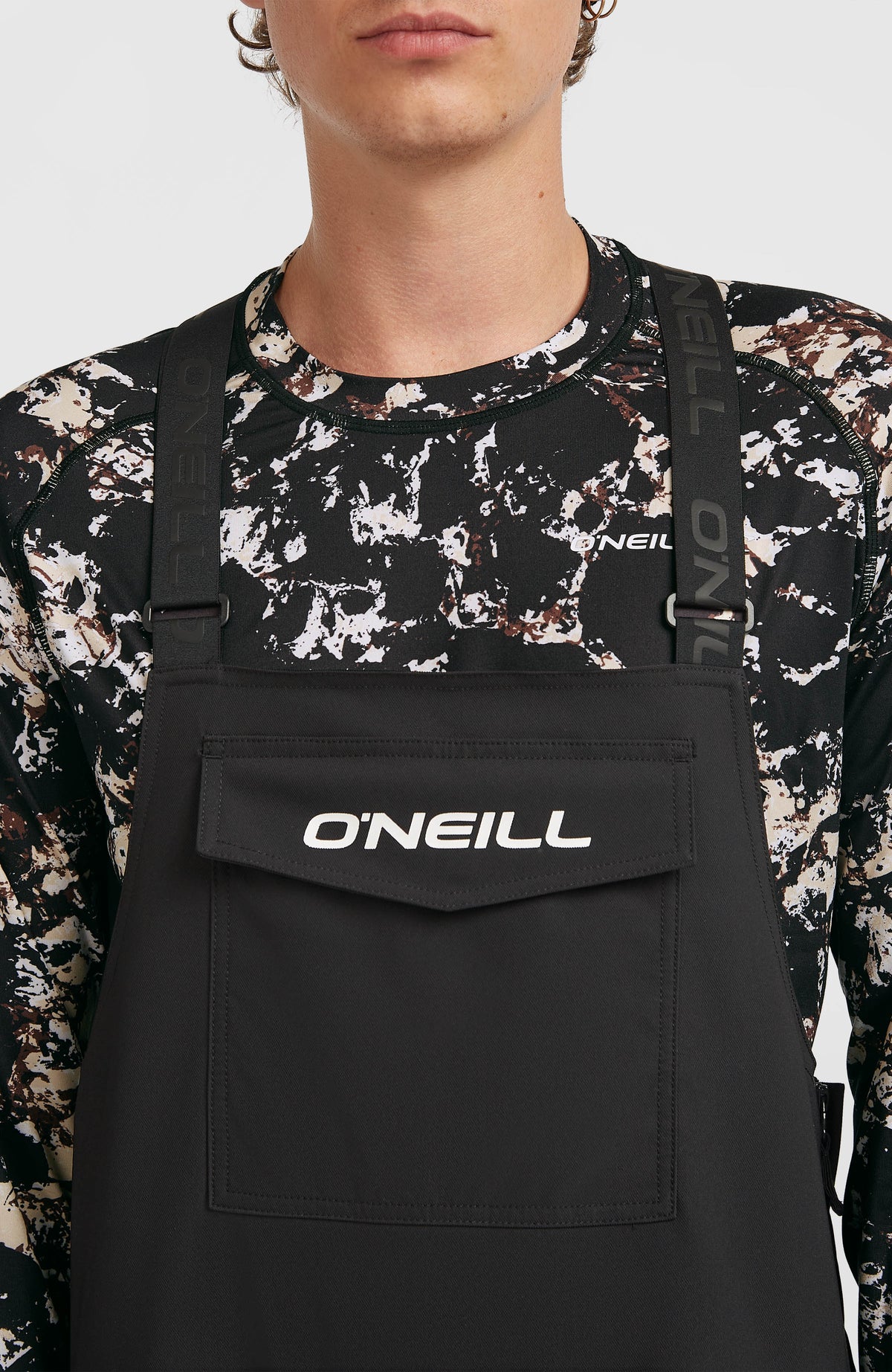 Nahaufnahme von Brustlatz mit Logo-Print und Trägern der schwarzen FWC'Peak Bib Skihose