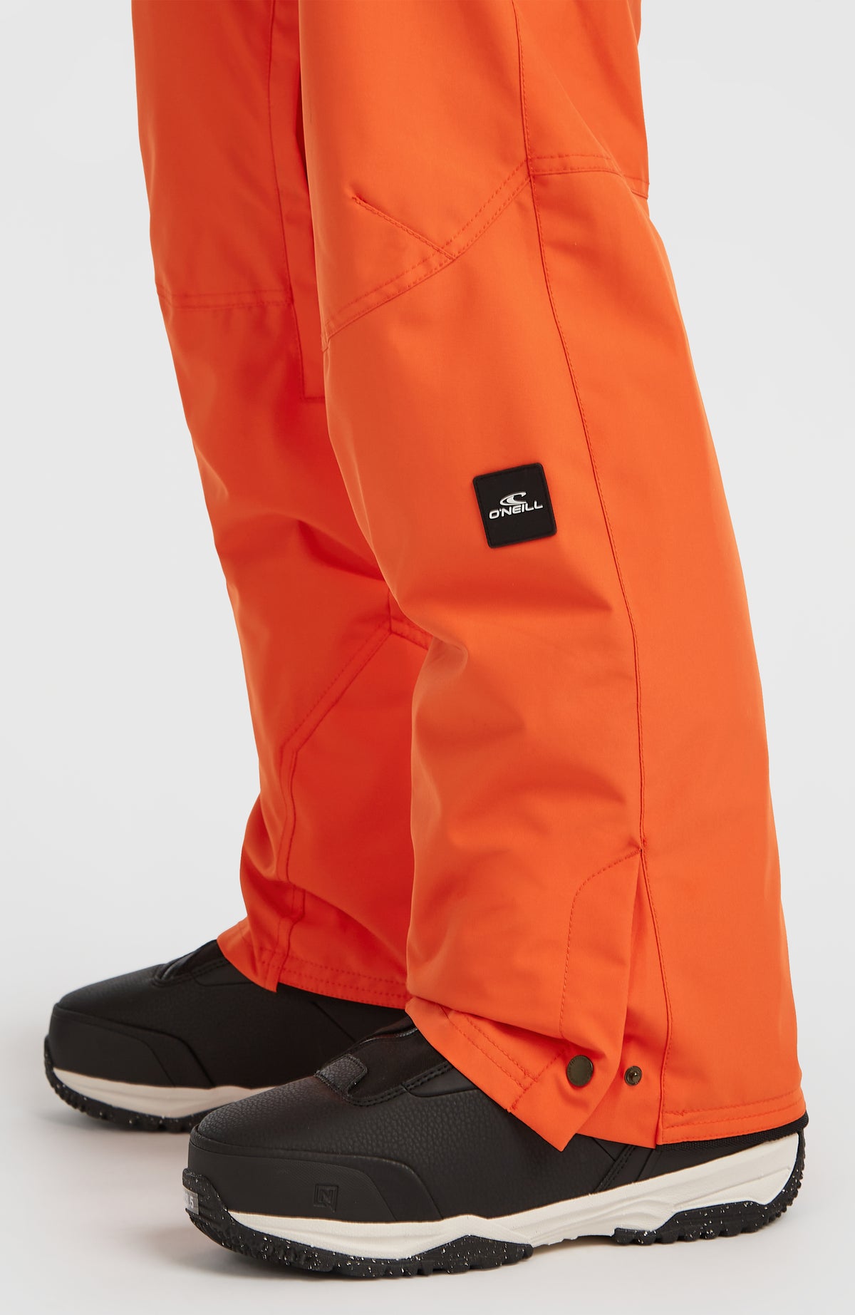 Nahaufnahme des unteren Hosenbeins der roten FWC'Cruz Skihose mit Logo-Patch und Druckknöpfen