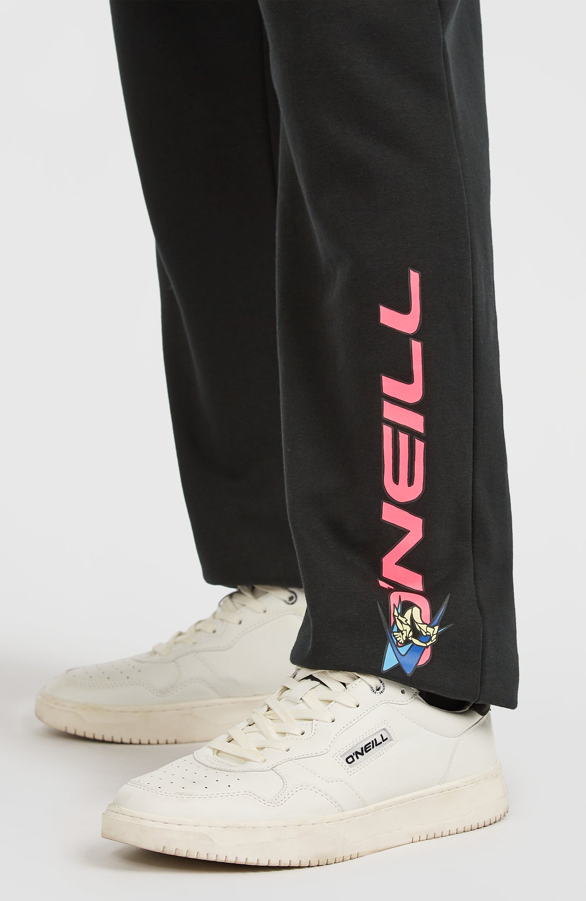 Nahaufnahme des Logo-Prints in Pink am Hosenbein der schwarzen FWC'Play Jogginghose für Herren am Model