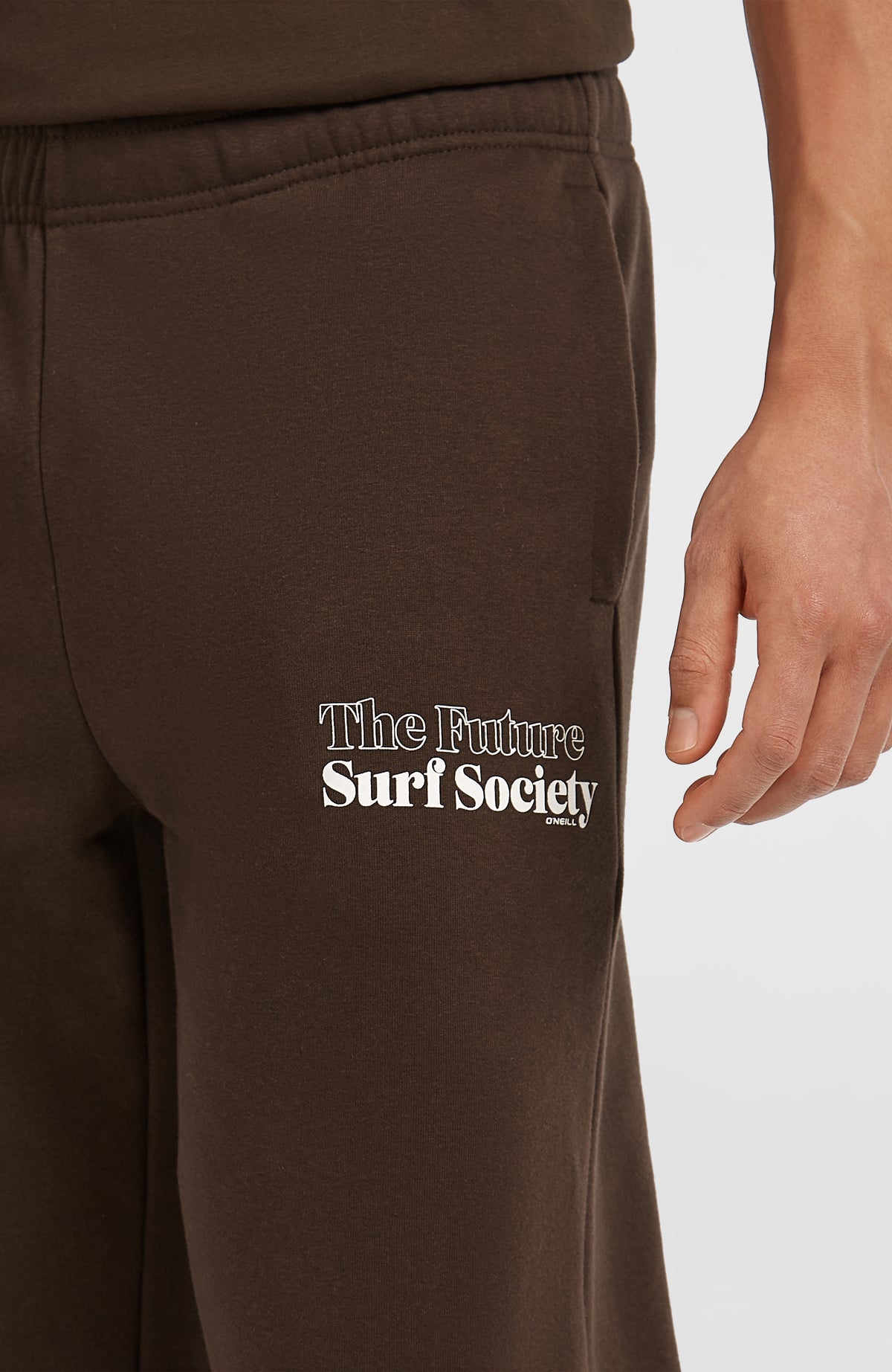 Nahaufnahme des weißen Logo-Prints neben der Seitentasche der braunen Future Surf Society Jogginghose